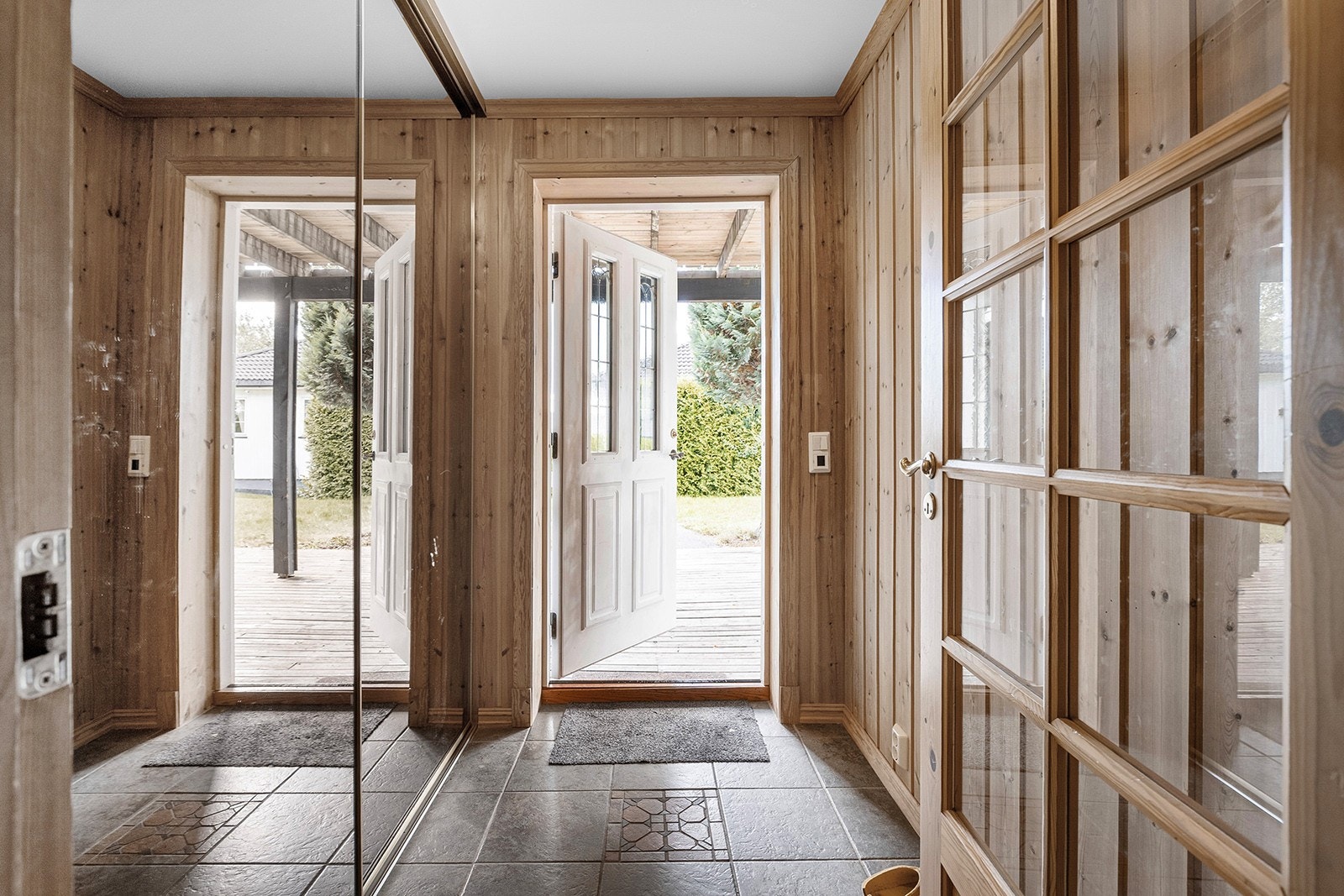 Adkomst via terrassen til en flislagt entré med skyvedørsgarderobe med speildører. Her er det god plass til å rydde unna yttertøy, samt til å ta imot gjester. Galleribilde