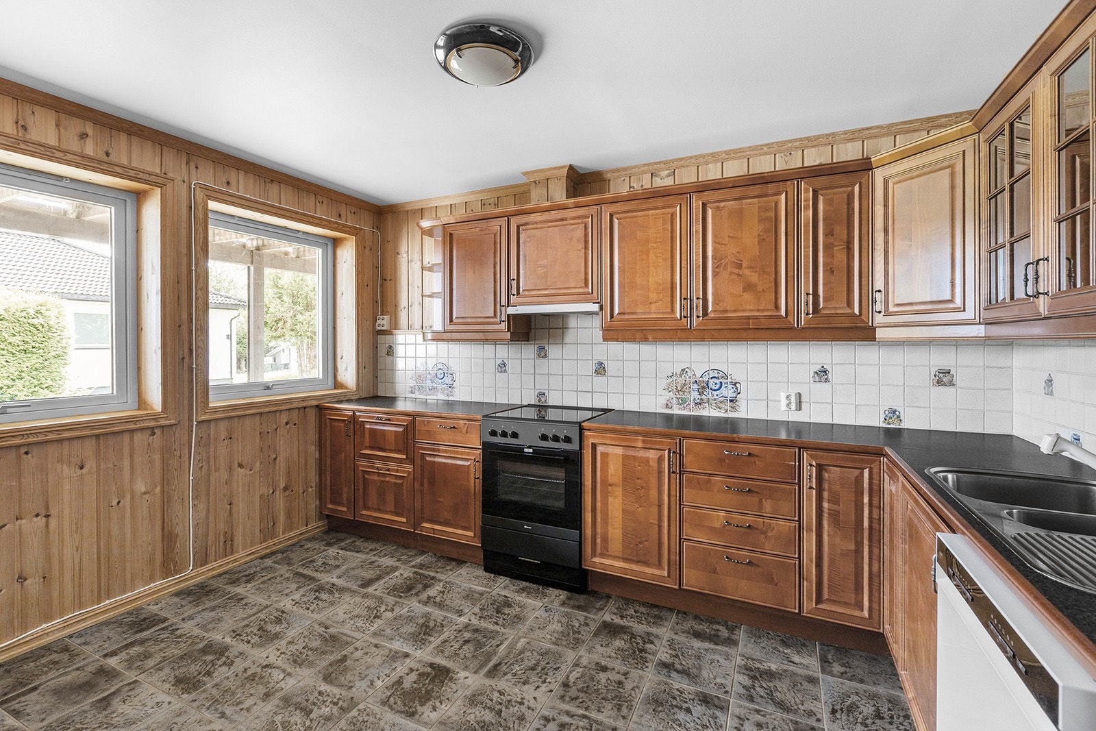 Stort kjøkken med rikelig benke- og skapplass, innredet med frittstående komfyr, oppvaskmaskin og kjøleskap med frysedel. Galleribilde