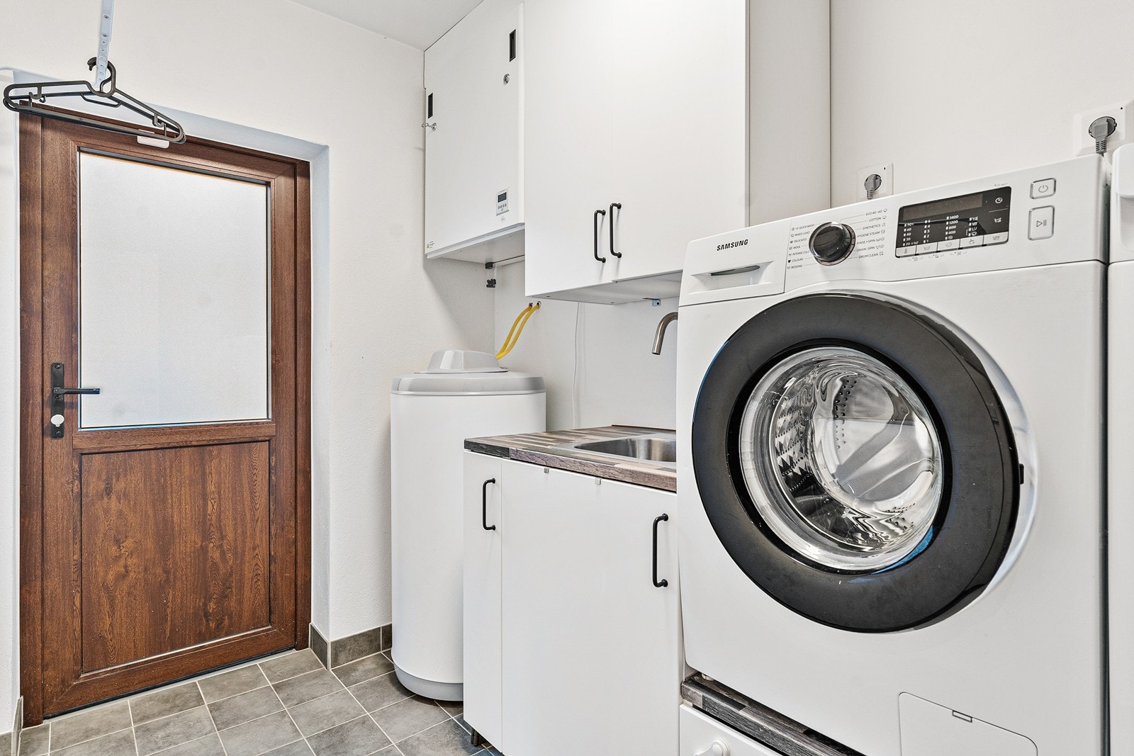 Via kjøkkenet er det adkomst til vaskerommet, som har slette, malte overflater på vegger og himling, samt keramiske fliser på gulv Galleribilde