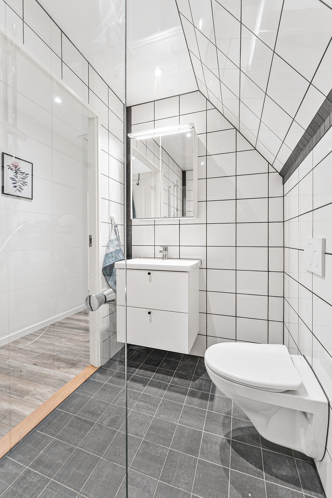 Badet er helfliset og utstyrt med baderomsinnredning med heldekkende servant og ettgreps blandebatteri, vegghengt toalett samt dusjsone med garnityr og glassvegg Galleribilde