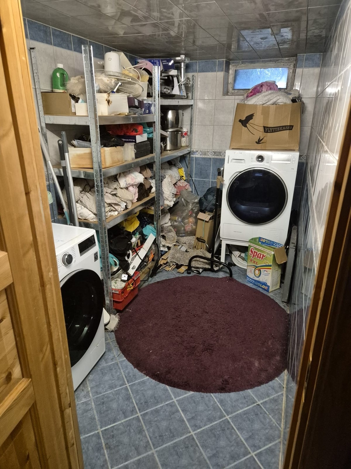 I kjelleren er det et kombinert bad og vaskerom fra byggeåret 1956. Rommet har fliser på gulv, vegger og i himling, og det er opplegg for vaskemaskin. Galleribilde