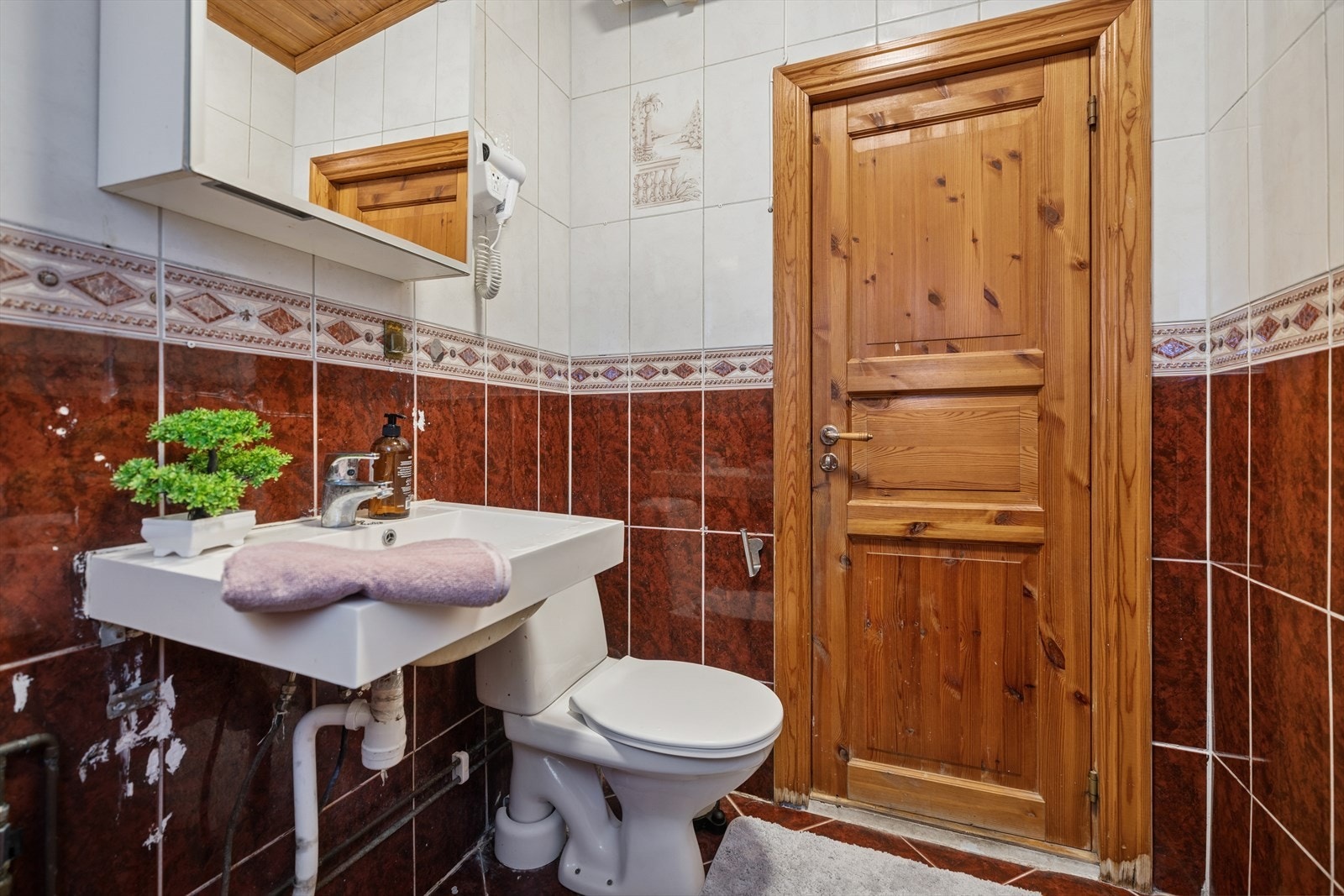 Rommet er innredet med toalett, servant nedfelt i innredning og et dusjhjørne. Galleribilde