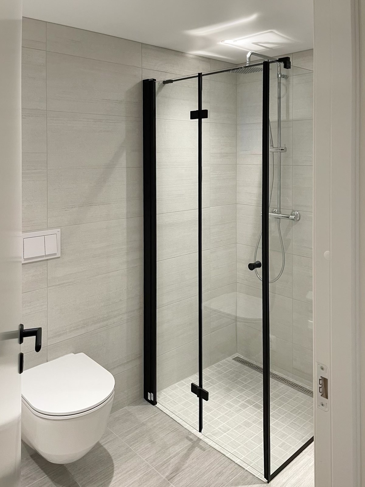 Lekkert dusjhjørne med mosaikkfliser på gulv. Galleribilde