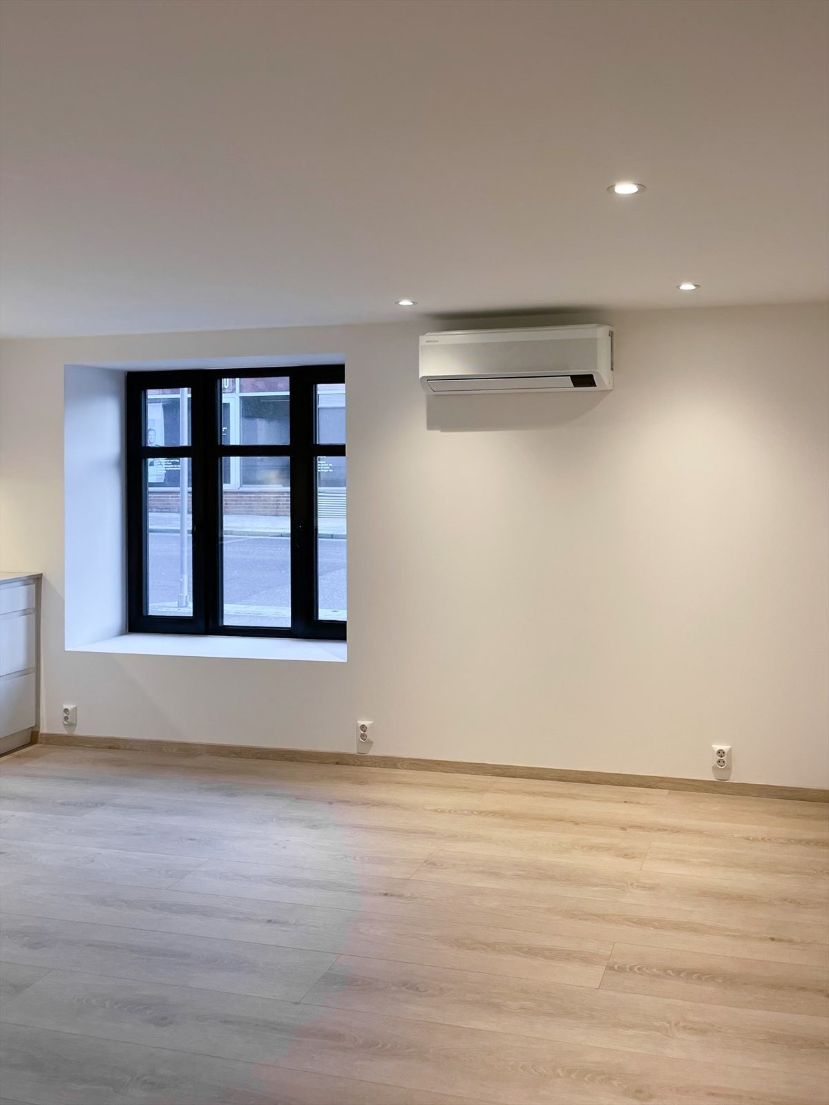 Romslig stue i åpen løsning mot kjøkken. Rommet oppleves lyst og luftig med spotter i tak, lyse flater og store vindusflater. Galleribilde