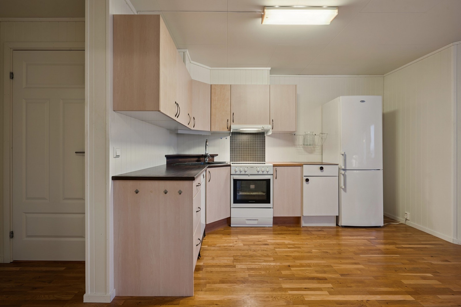 Kjøkkenet er utstyrt med frittstående hvitevarer som kjøl/fryseskap, oppvaskmaskin og komfyr Galleribilde