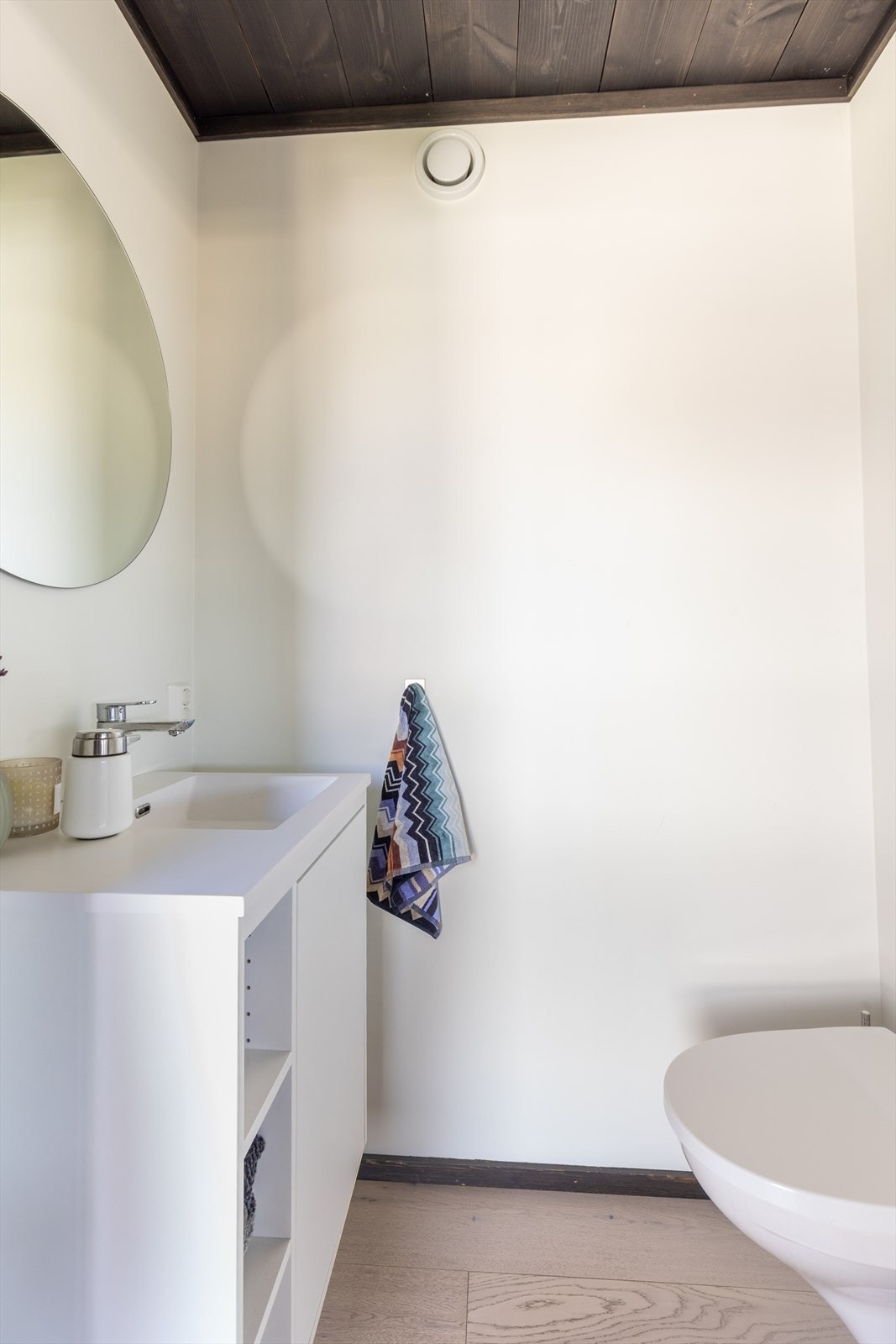 Eget gjestetoalett med enkel innredning, servant og veggmontert toalett. Parkett på gulv. Galleribilde