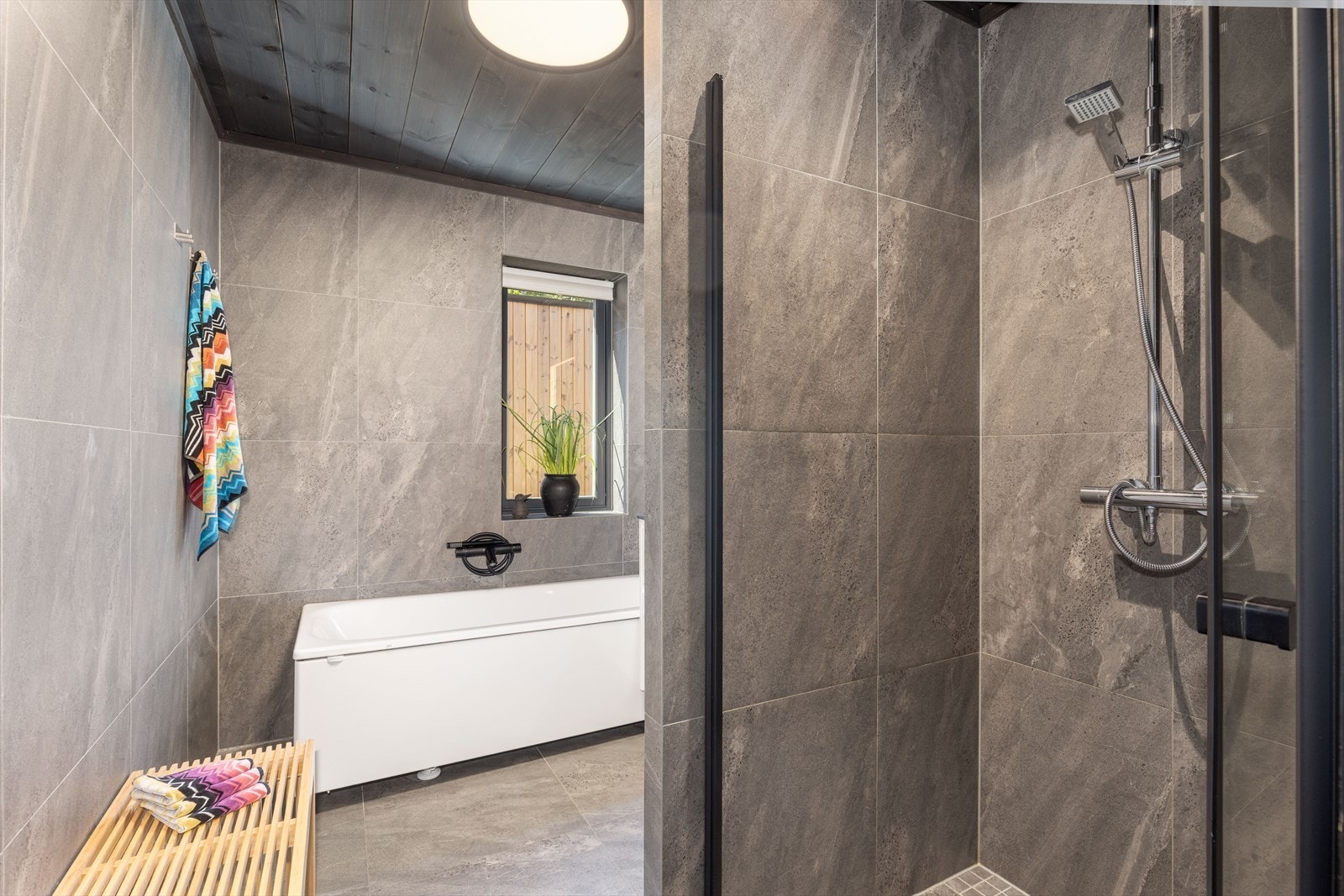 Badet er også innredet med nedsenket dusjhjørne, badekar og veggmontert toalett. Galleribilde