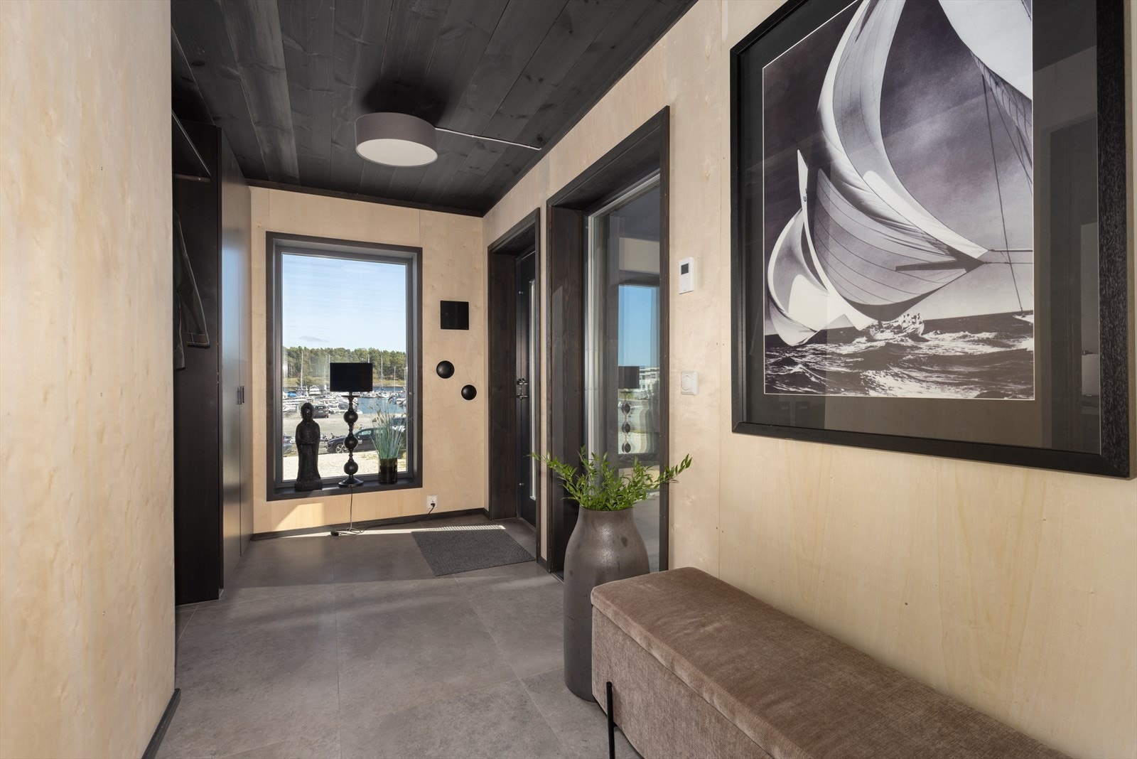 Boligen har et smakfullt gangareal med en lun fargepalett og flislagt gulv. Her er en praktisk nisje til klesoppbevaring. Galleribilde