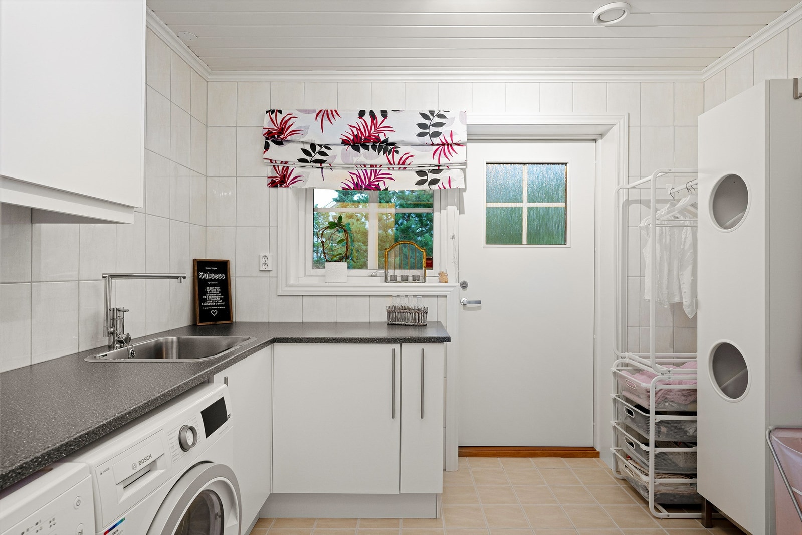 Vaskerommet er praktisk innredet til sitt formål. Gjennom ytterdøren kan klesvasken enkelt bæres ut i friluft. Tørkestativ er montert få meter unna. Galleribilde