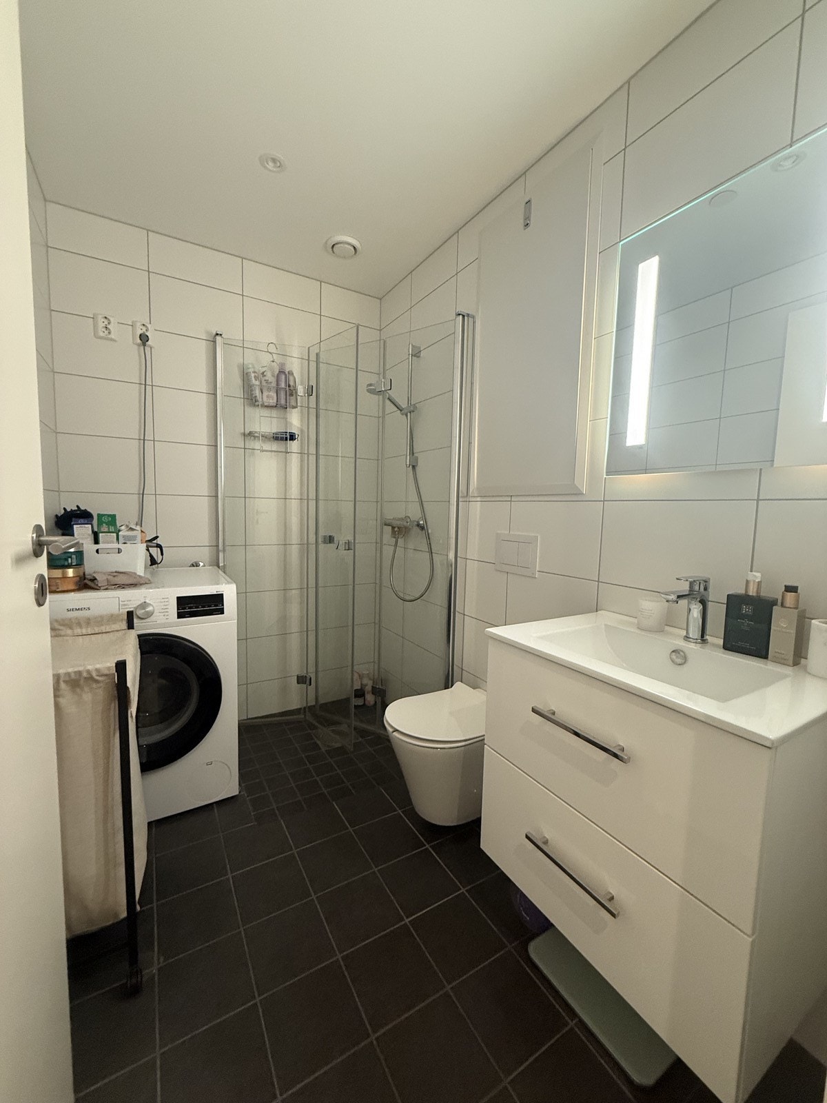 Flislagt bad med hjørnedusj, toalett og servant m/innredning. Opplegg for vaskemaskin Galleribilde