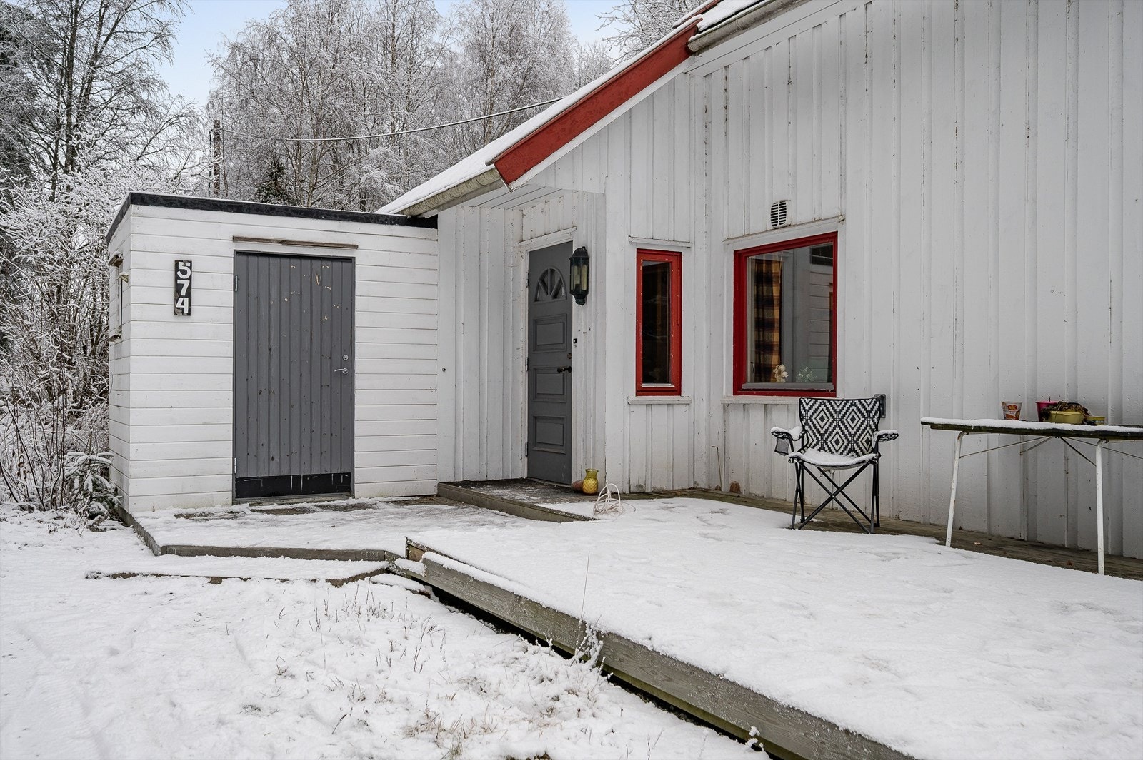 Inngangsparti med terrasseplatting og inntilbygget bod. Boden fremkommer ikke av mottatt byggetegninger. Galleribilde