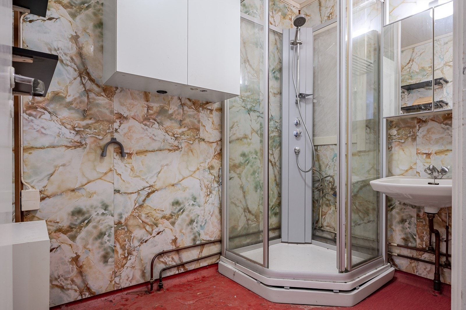 Bad i 1. etasje med dusjkabinett og servant. Det er behov for renovering av badet for å tilfredsstille dagens krav til standard. Det har fått tilstandsgrad 3 i tilstandsrapporten. Galleribilde