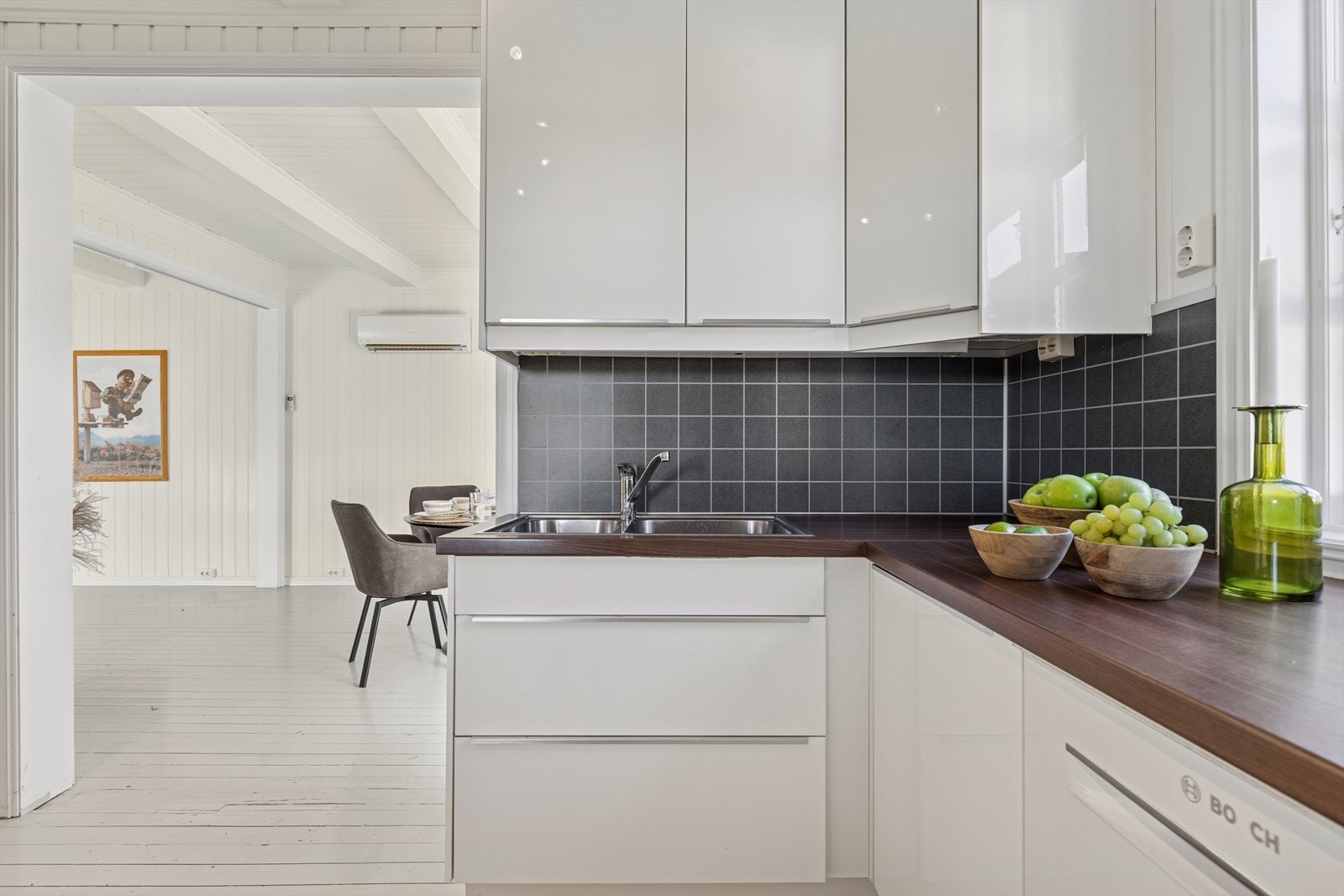 Kjøkkeninnredning med hvite, høyglans fronter og laminat benkeplate. Galleribilde