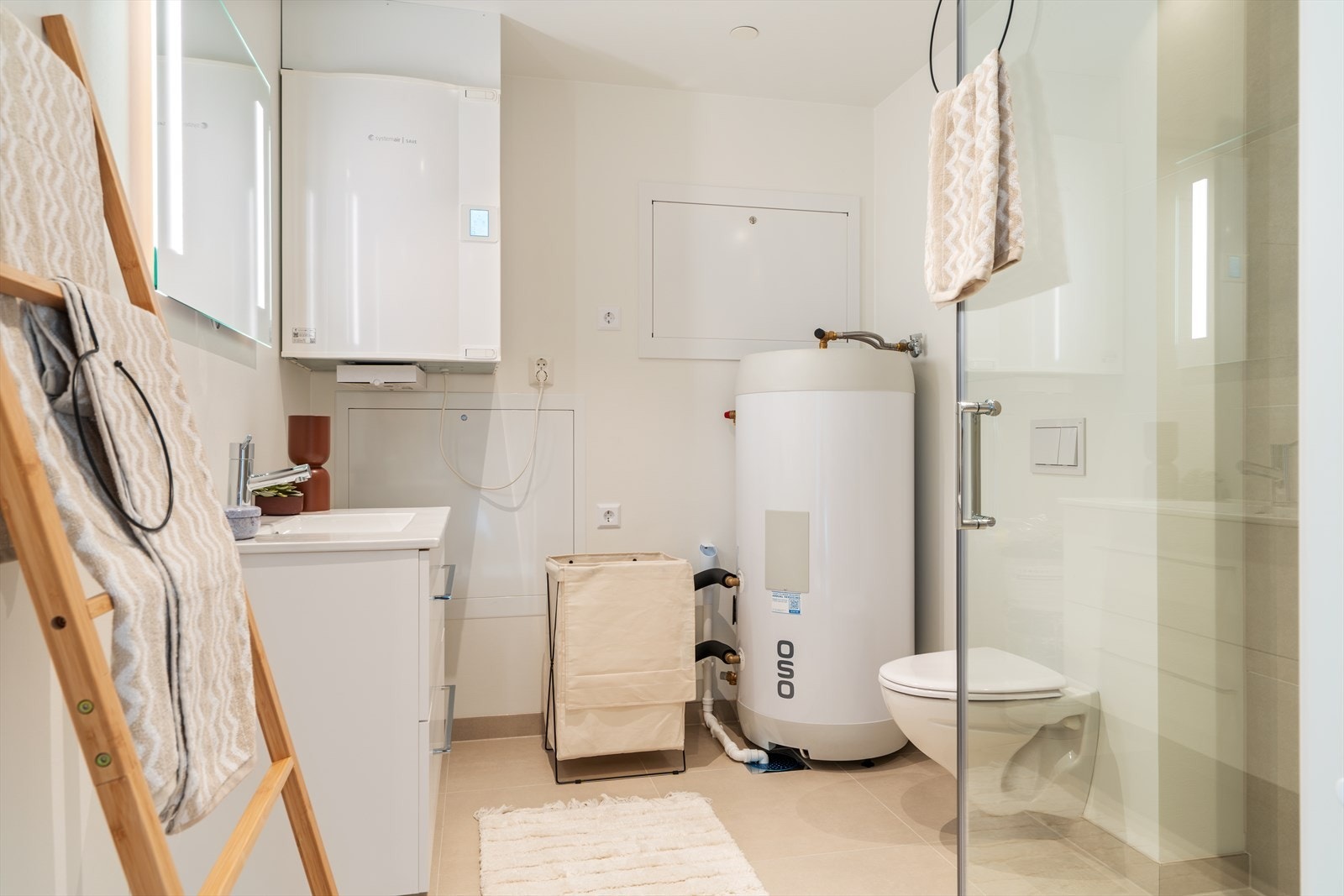 Leiligheten har et delikat bad med fliser på gulv og malte vegger. Rommet er utstyrt med dusjhjørne med fliser, vegghengt toalett og moderne baderomsinnredning med høyglans skuffer og servant. Badet har opplegg for vaskemaskin. Galleribilde