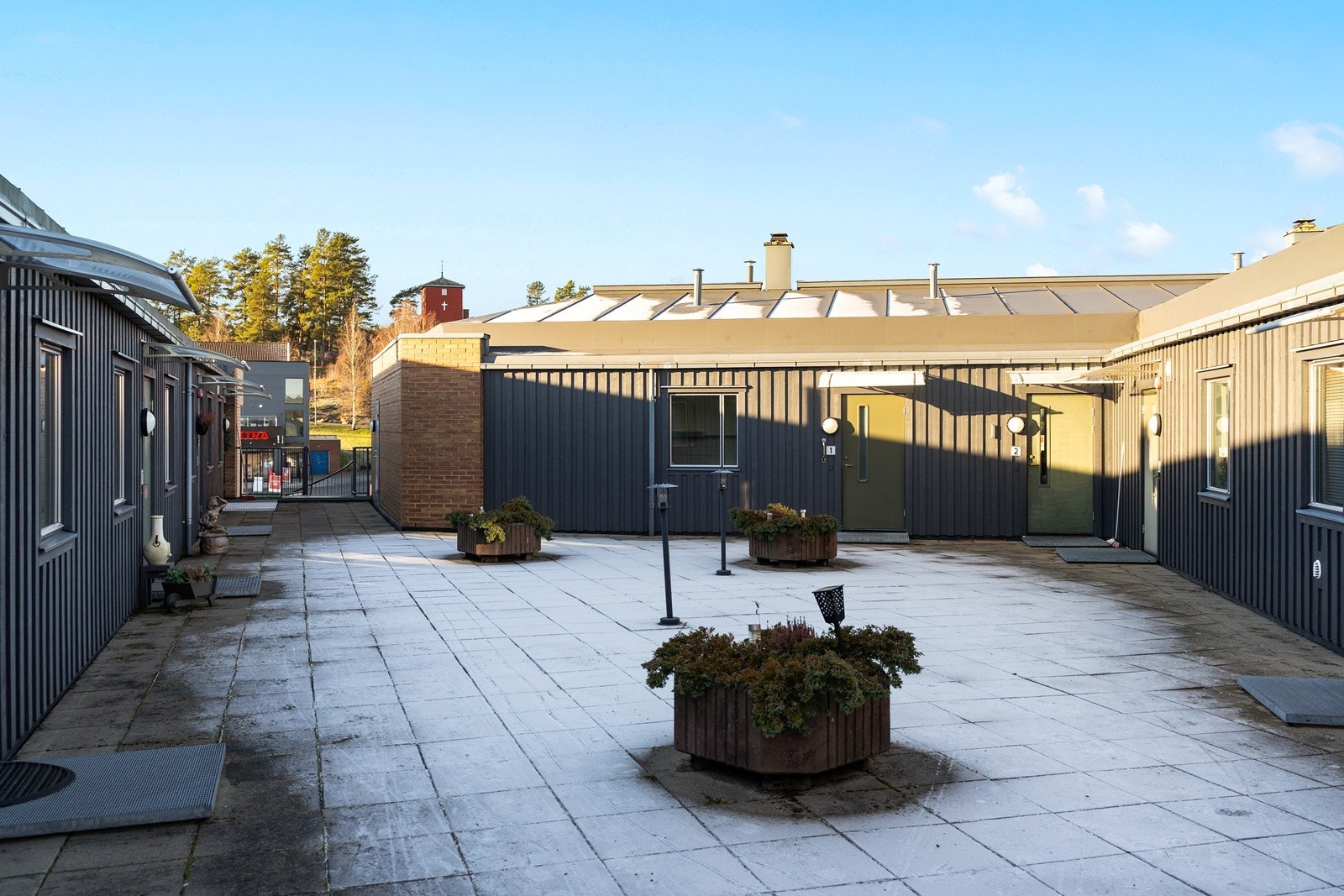 Felles atrium med betongheller og utebelysning gir en sosial møteplass. Galleribilde