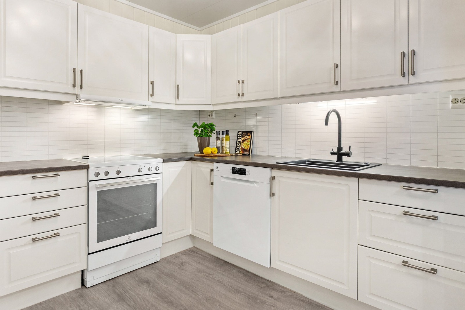 Stilren innredning med integrert oppvaskmaskin, samt avsatt plass for komfyr og kjøleskap Galleribilde