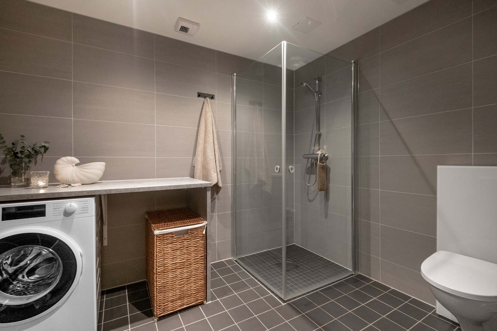 Badet er moderne og tidløst, hvor rommet er helfliset med fliser på både gulv og vegger, og gulvvarme sørger for en behagelig komfort. Galleribilde