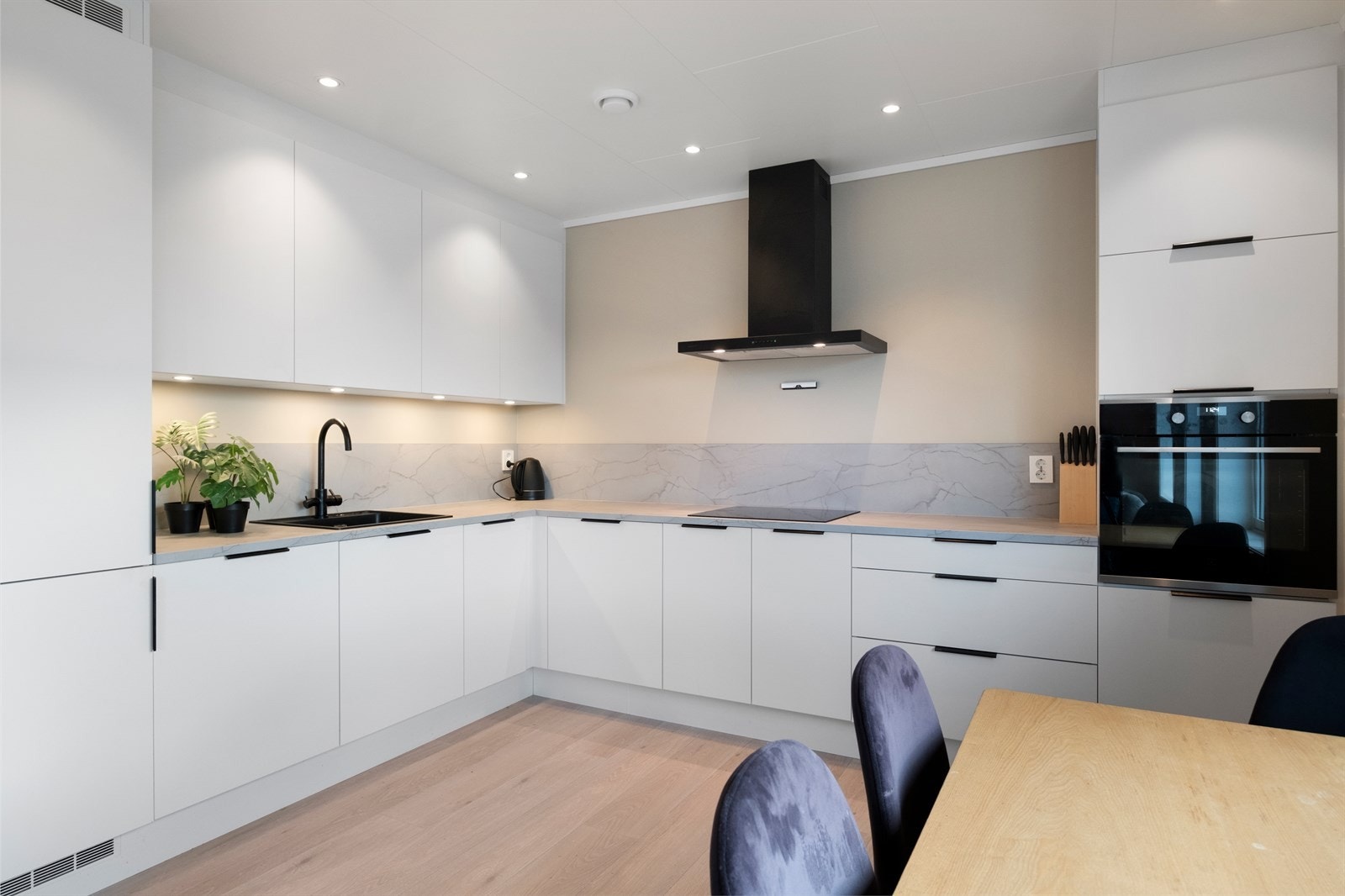 Kjøkkenet er utstyrt med glatte hvite fronter og integrerte hvitevarer. Galleribilde