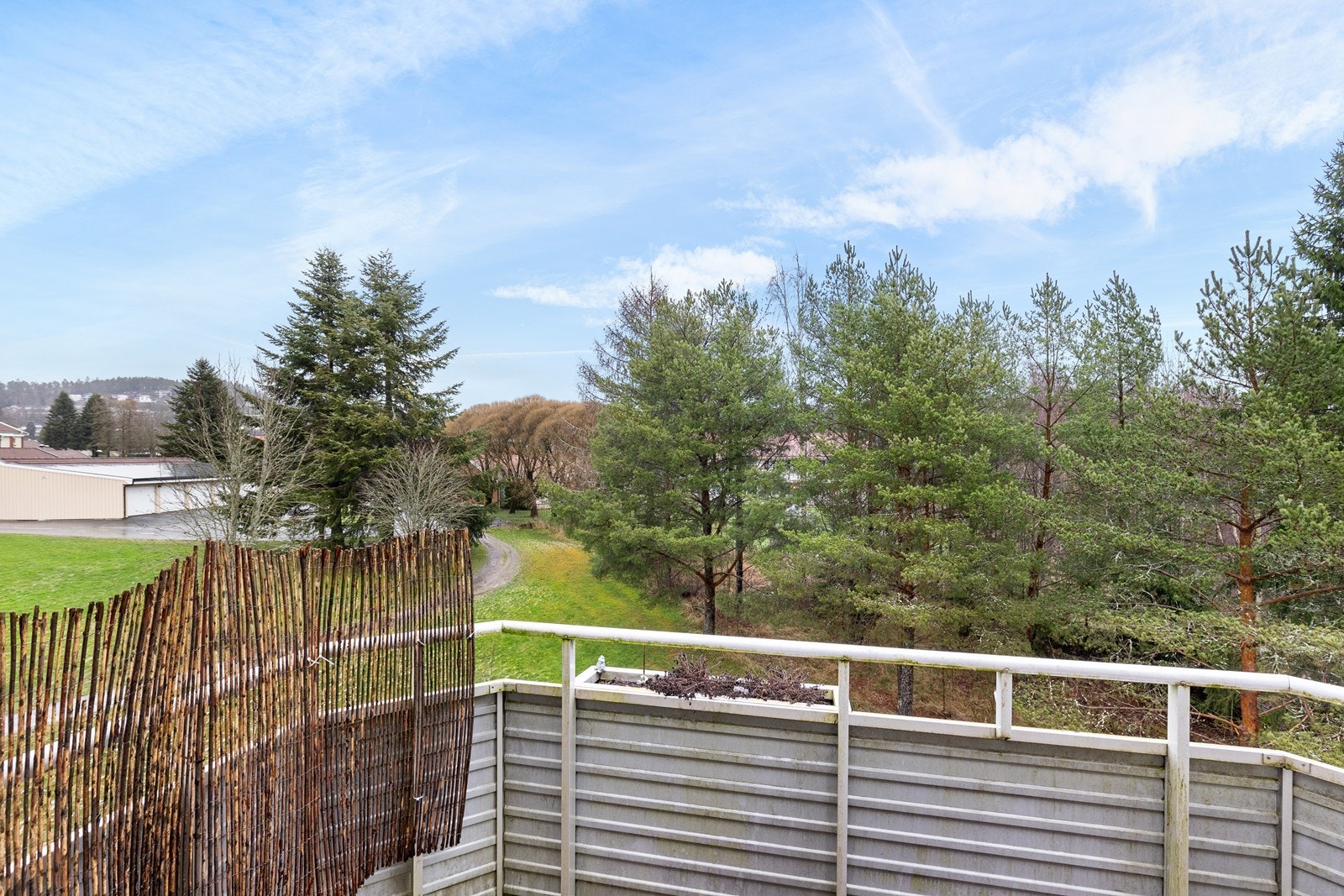 Fra balkongen kan man nyte utsikten mot det grønne landskapet og nærliggende trær. Galleribilde