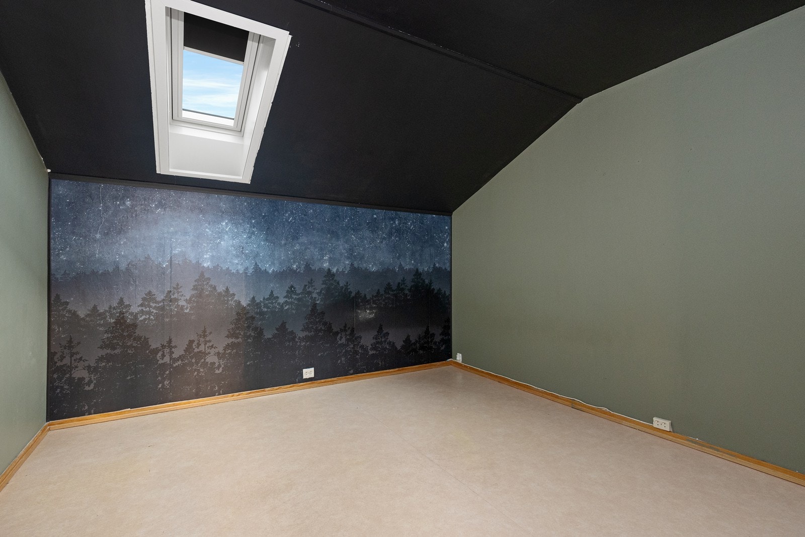 Tapet med skogsmotiv dekker veggen, og takvindu gir lys til rommet med skråtak. Galleribilde