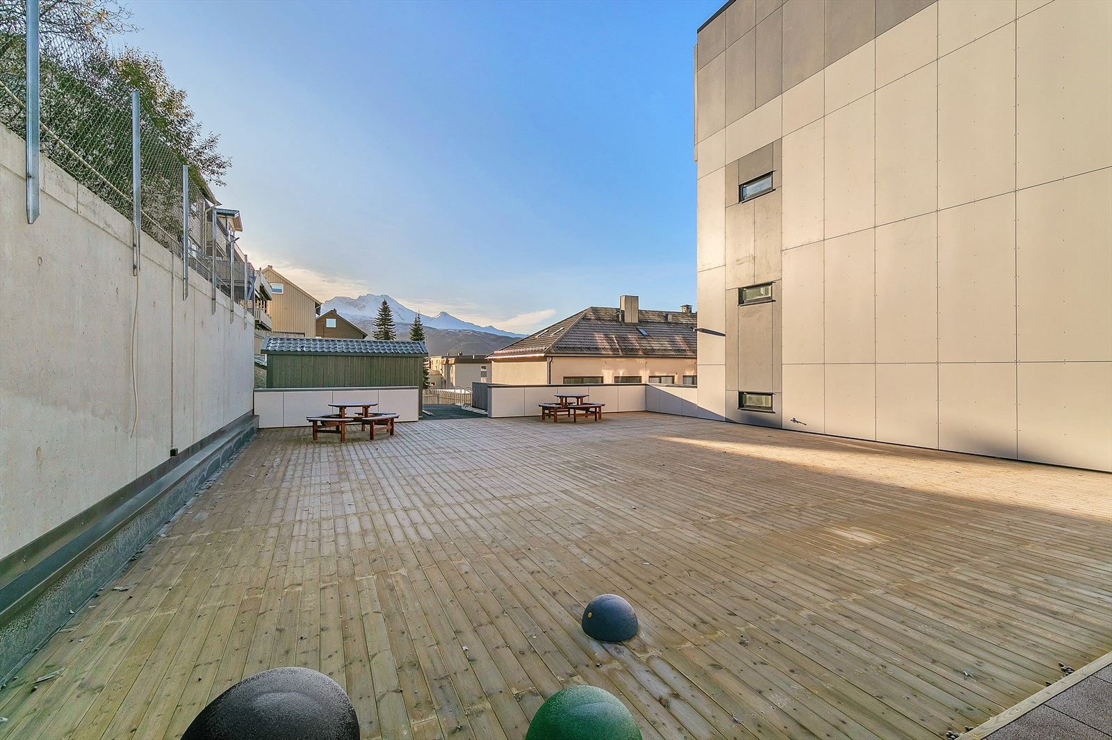 Felles terrasse som er utstyrt med benker og lekeapparat Galleribilde