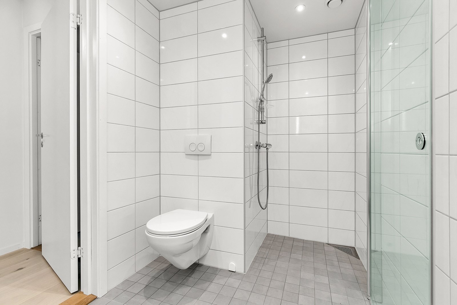 Badet er velutstyrt med velplasserte downlights i himling, behagelig gulvvarme, vegghengt toalett, dusjhjørne og servantskap med heldekkende servant Galleribilde