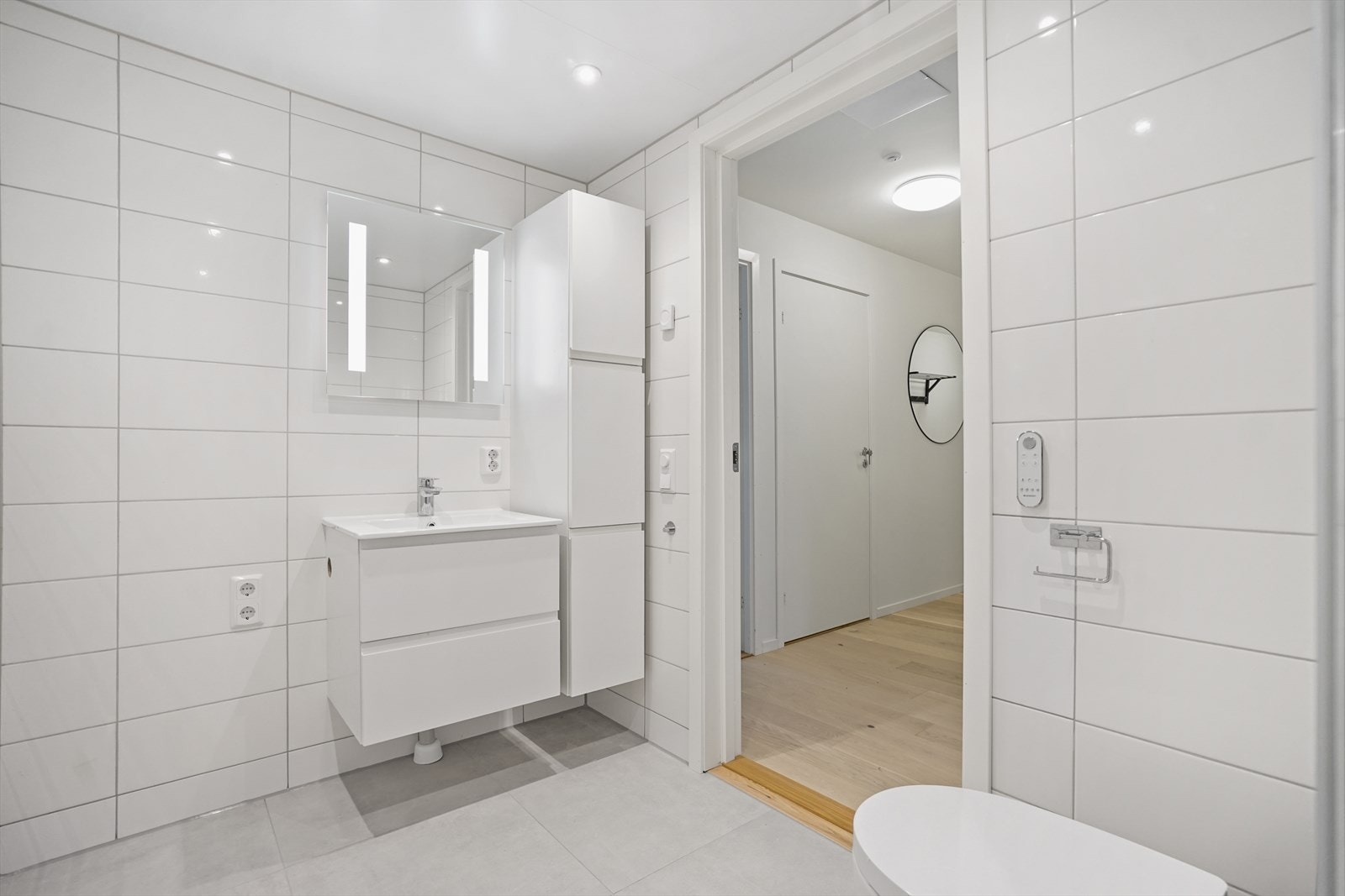 Badet har opplegg for vaskemaskin, servantskap, høyskap og speil med integrert belysning. Galleribilde