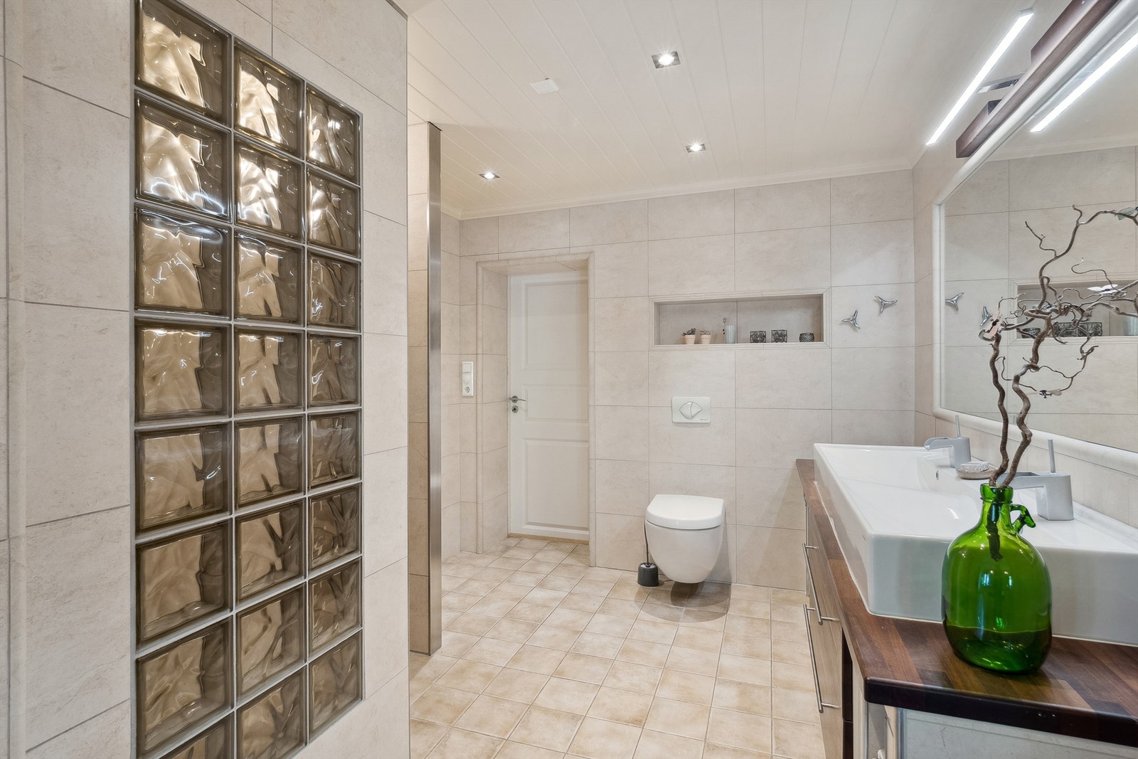 Det er en stor servantløsning med dobbel kum og egen flislagt nisje for dusjen Galleribilde