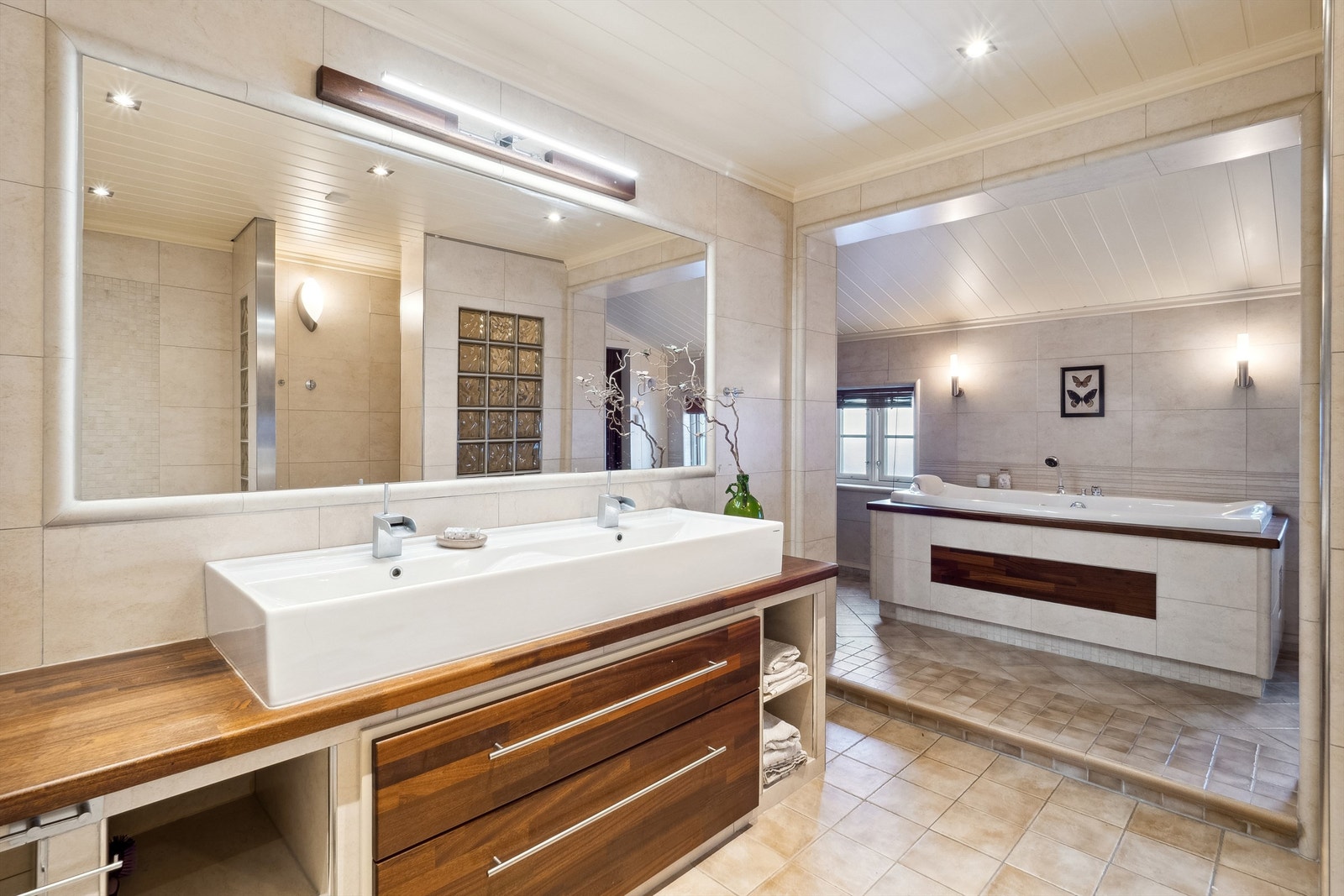 Badet er av meget god størrelse og er lekkert innredet med fliser og materialvalg i duse og behagelige fargekombinasjoner Galleribilde