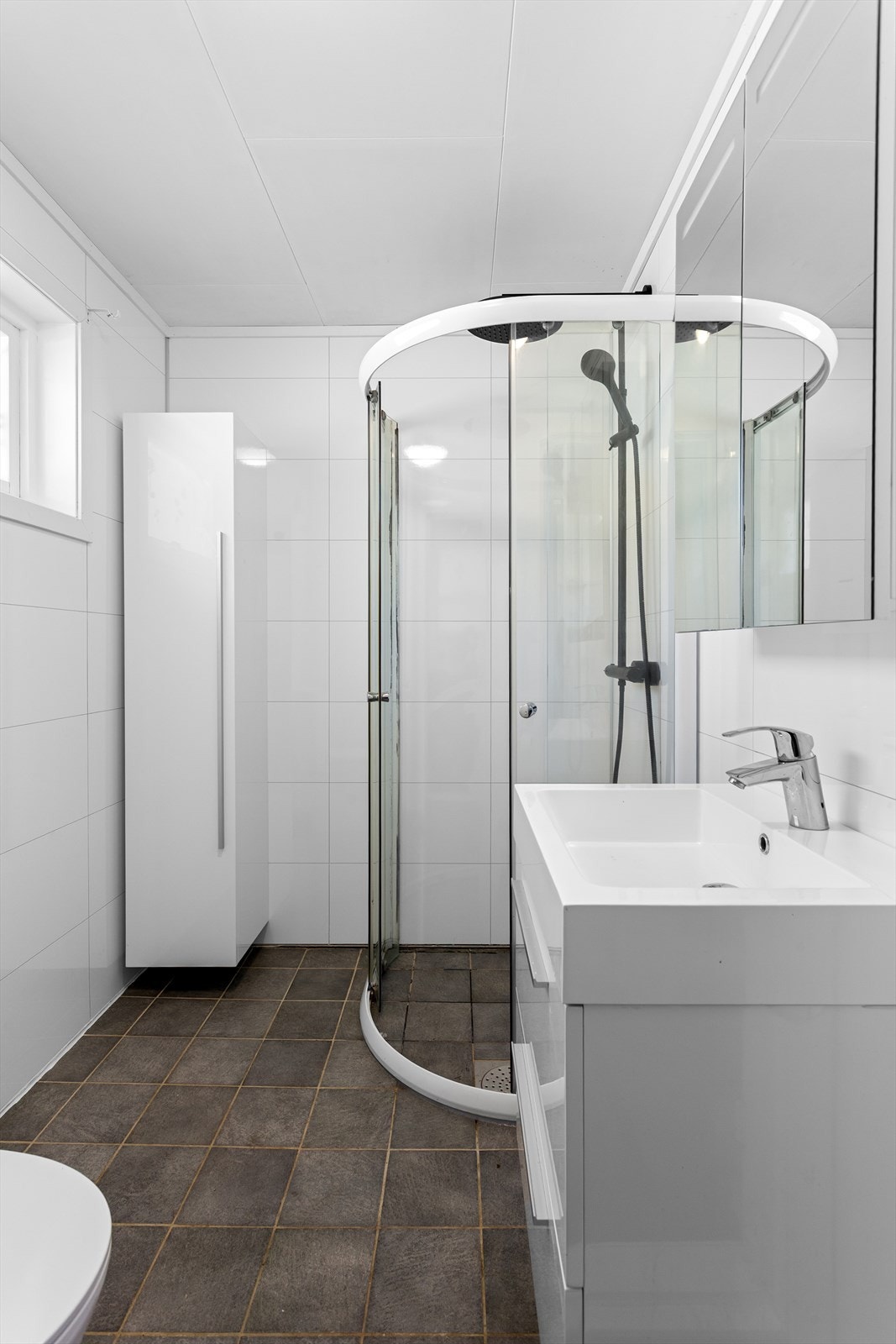 Bad med dusjhjørne som har skyvedørsramme og regnfallsdusj Galleribilde