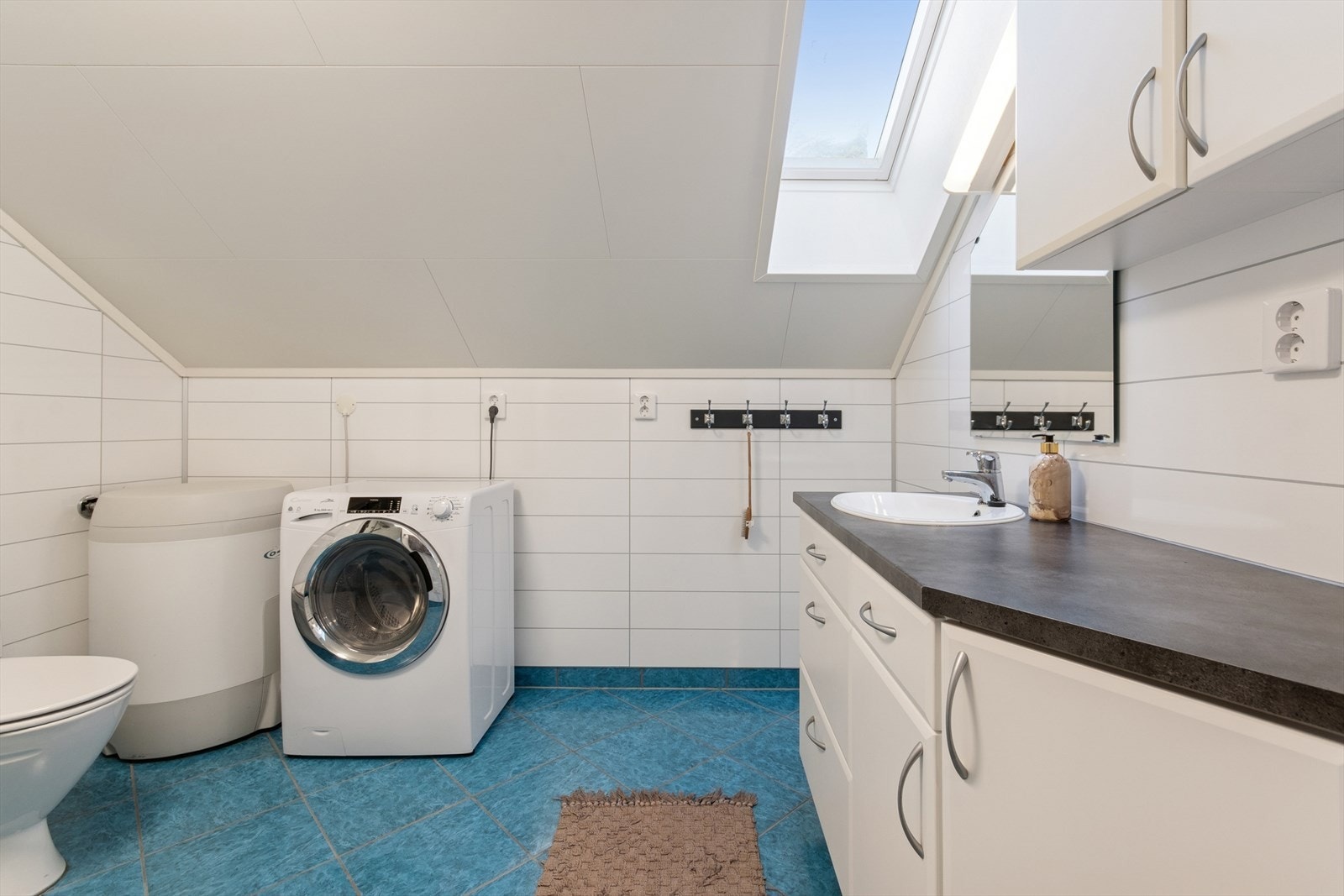 Lyst bad med flislagt gulv og baderomsplater på vegger. Galleribilde