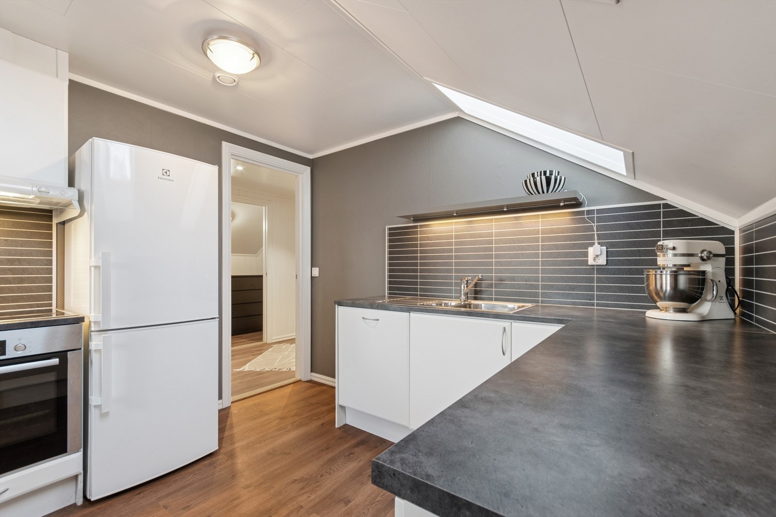 Lys og tidløs innredning med hvite slette fronter og benkeplate av typen laminat. Galleribilde