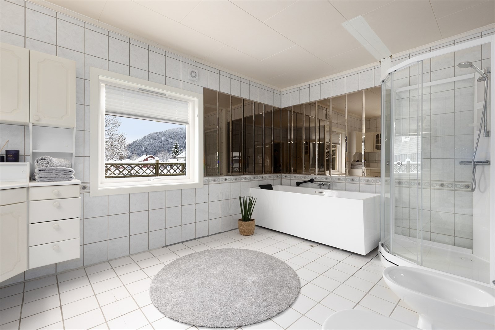 Stort, helfliset bad innredet med servantinnredning, toalett, bide, dusjkabinett og badekar. Det er ventilasjon via vifte på vegg. Galleribilde