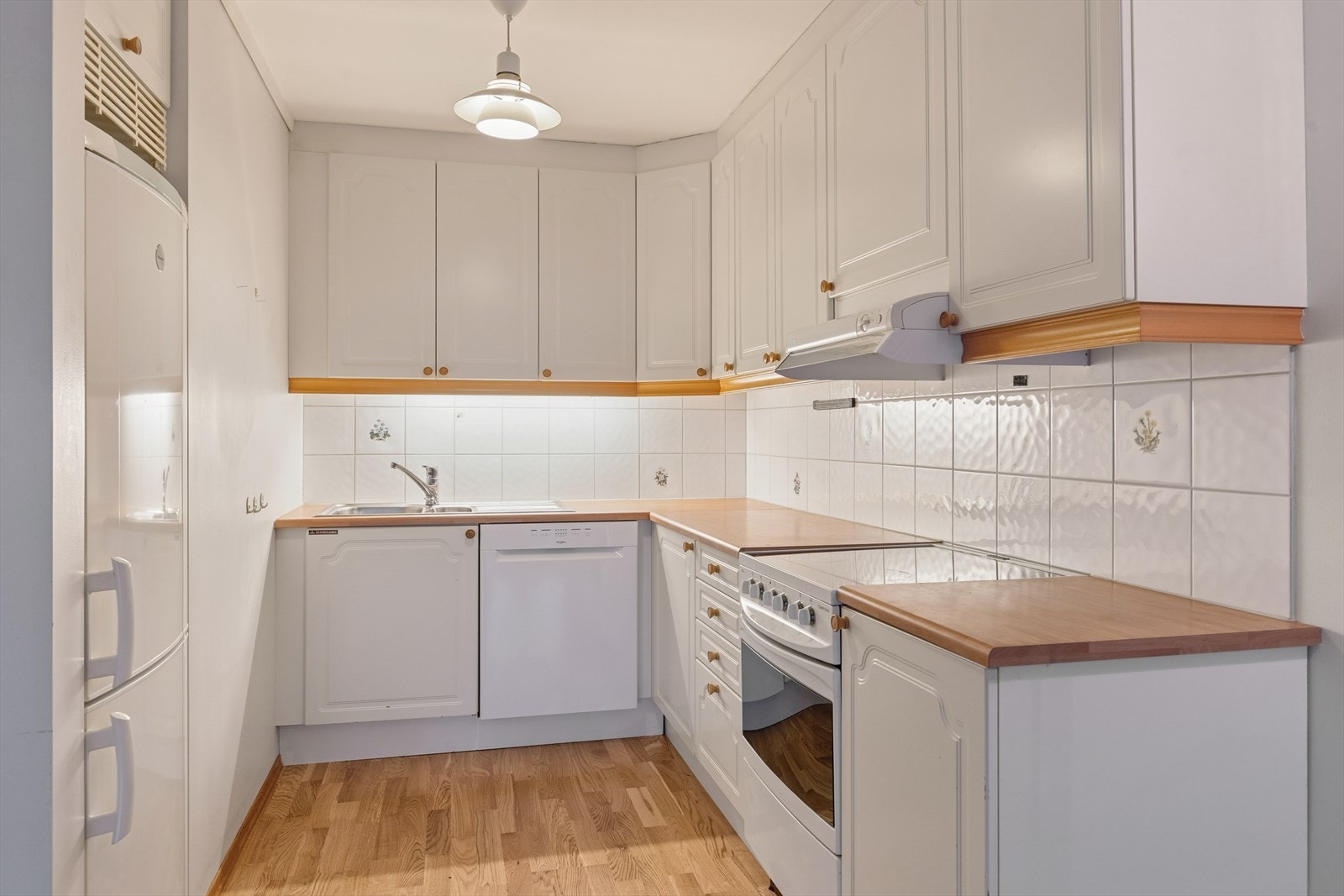 Kjøkkenet er innredet med hvite, profilerte fronter og trefarget benkeplate i laminat. Romslig kjøkken hvor man har godt med skap- og skuffeplass, samt gode arbeidsflater på benk. Galleribilde