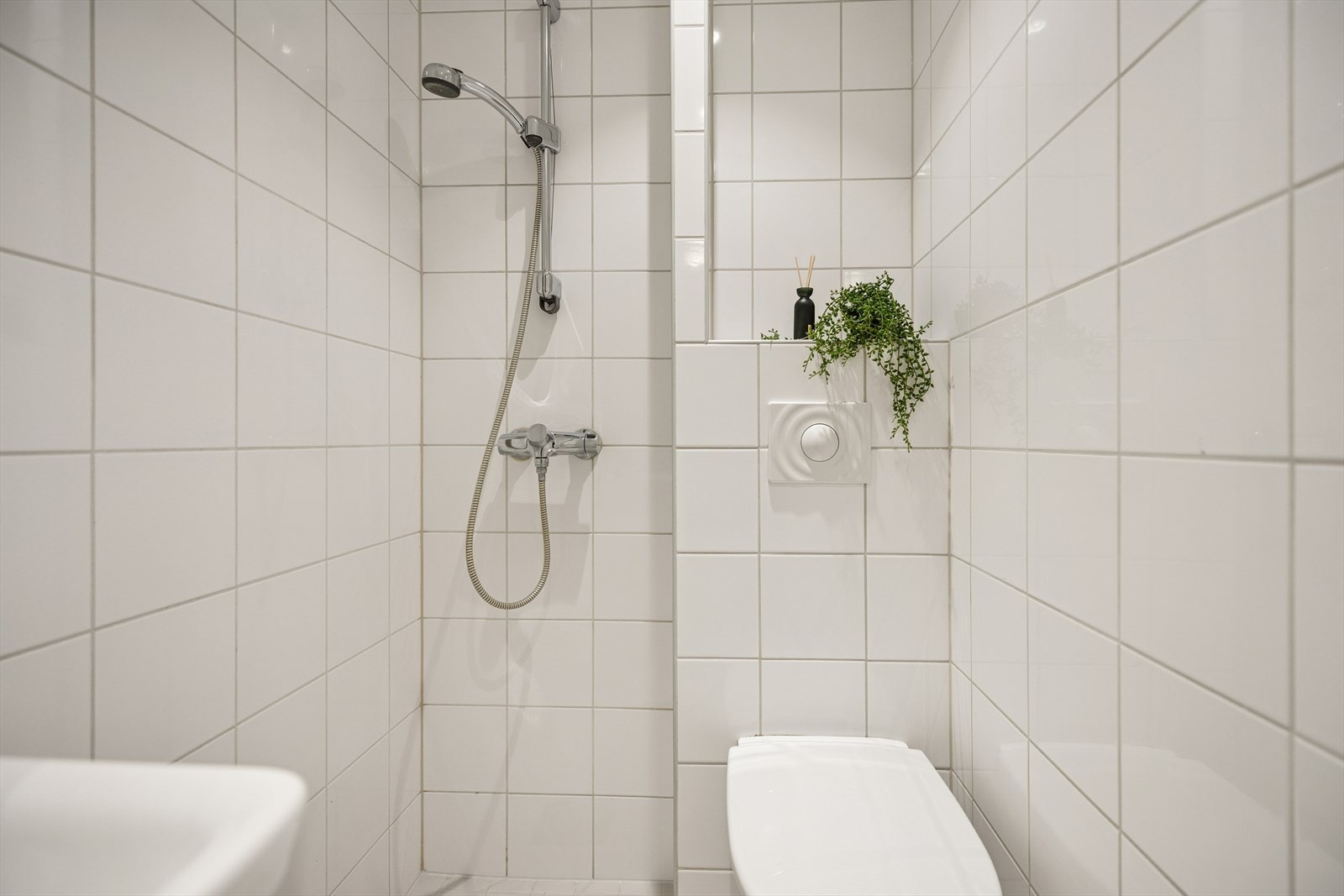 Bad/wc består av vegghengt wc, servant m/underskap, speil og åpen dusj. Galleribilde