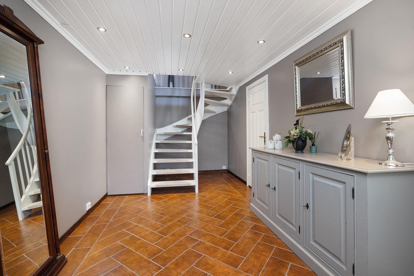 Romslig entré i underetasjen med trapp som leder opp til hovedetasjen. Galleribilde