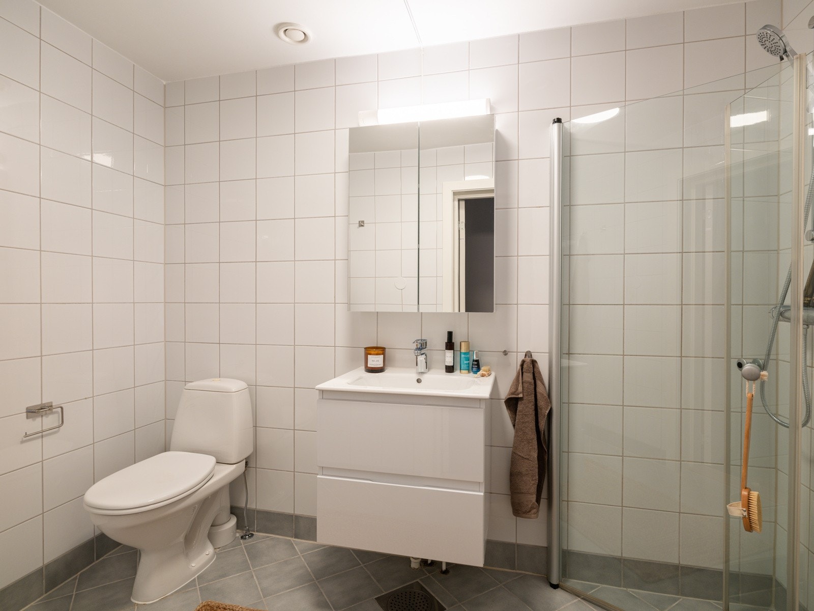 Leiligheten har et lyst og tidløst baderom som ble pusset opp i 2017. Baderommet har grå fliser på gulv, elektriske varmekabler, hvite fliser på veggene og mekanisk avtrekk. Galleribilde
