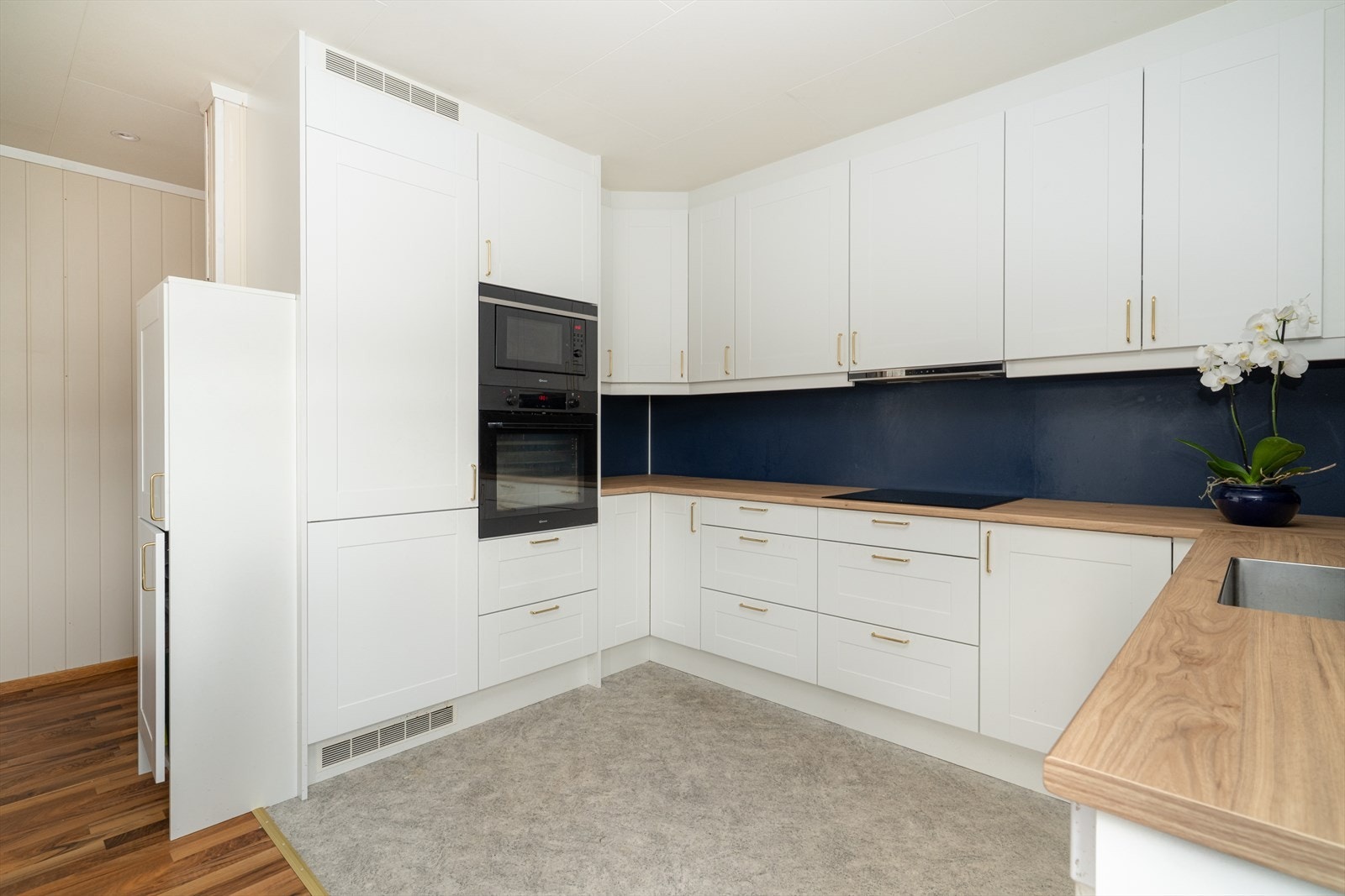 Vannfaste plater på vegg over laminat benkeplate med gode arbeidsflater, nedfelt platetopp og oppvaskkum i rustfritt stål. Galleribilde