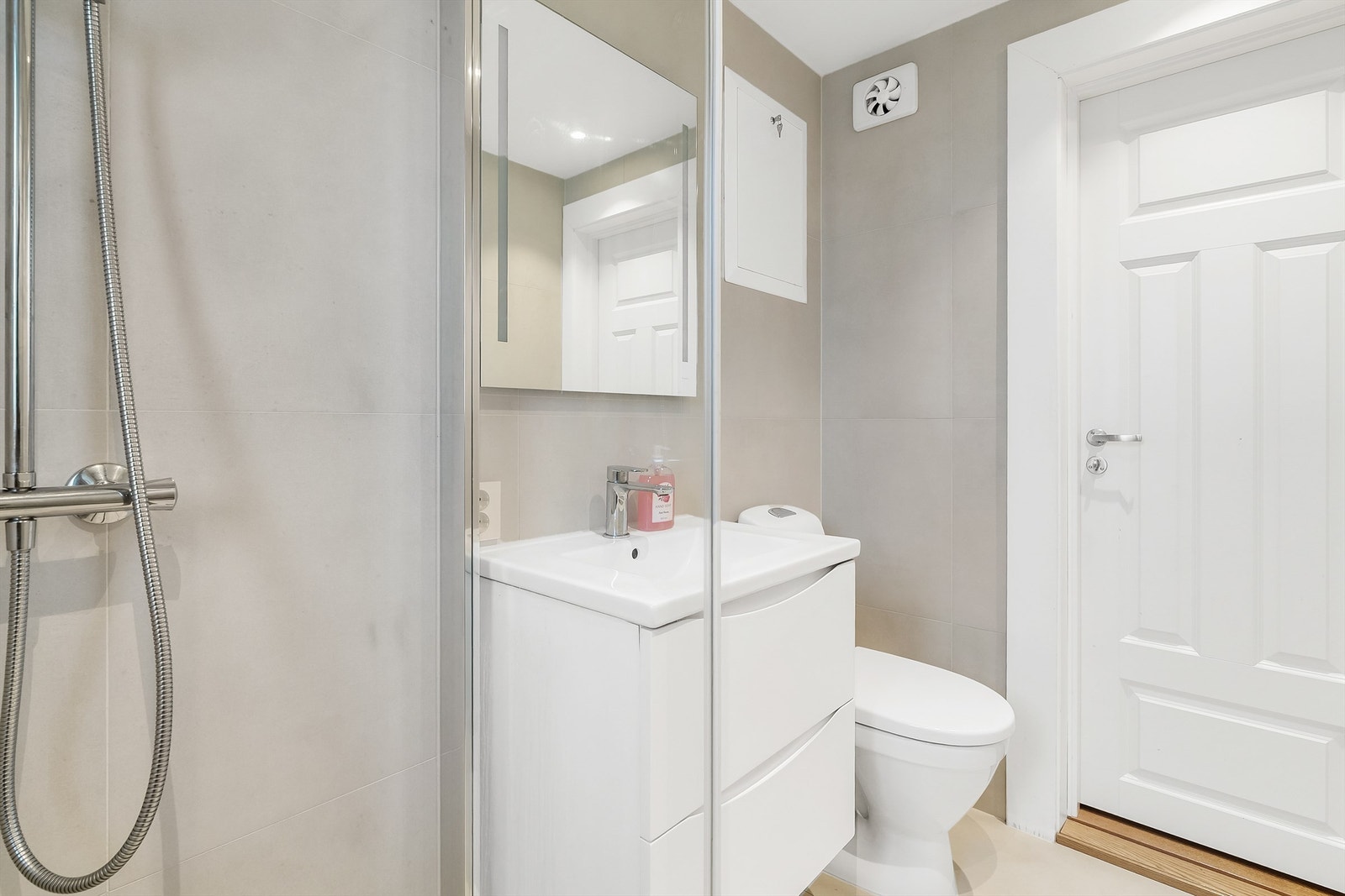 Badet er innredet med vegghengt servantinnredning, dusjnisje og gulvstående toalett Galleribilde