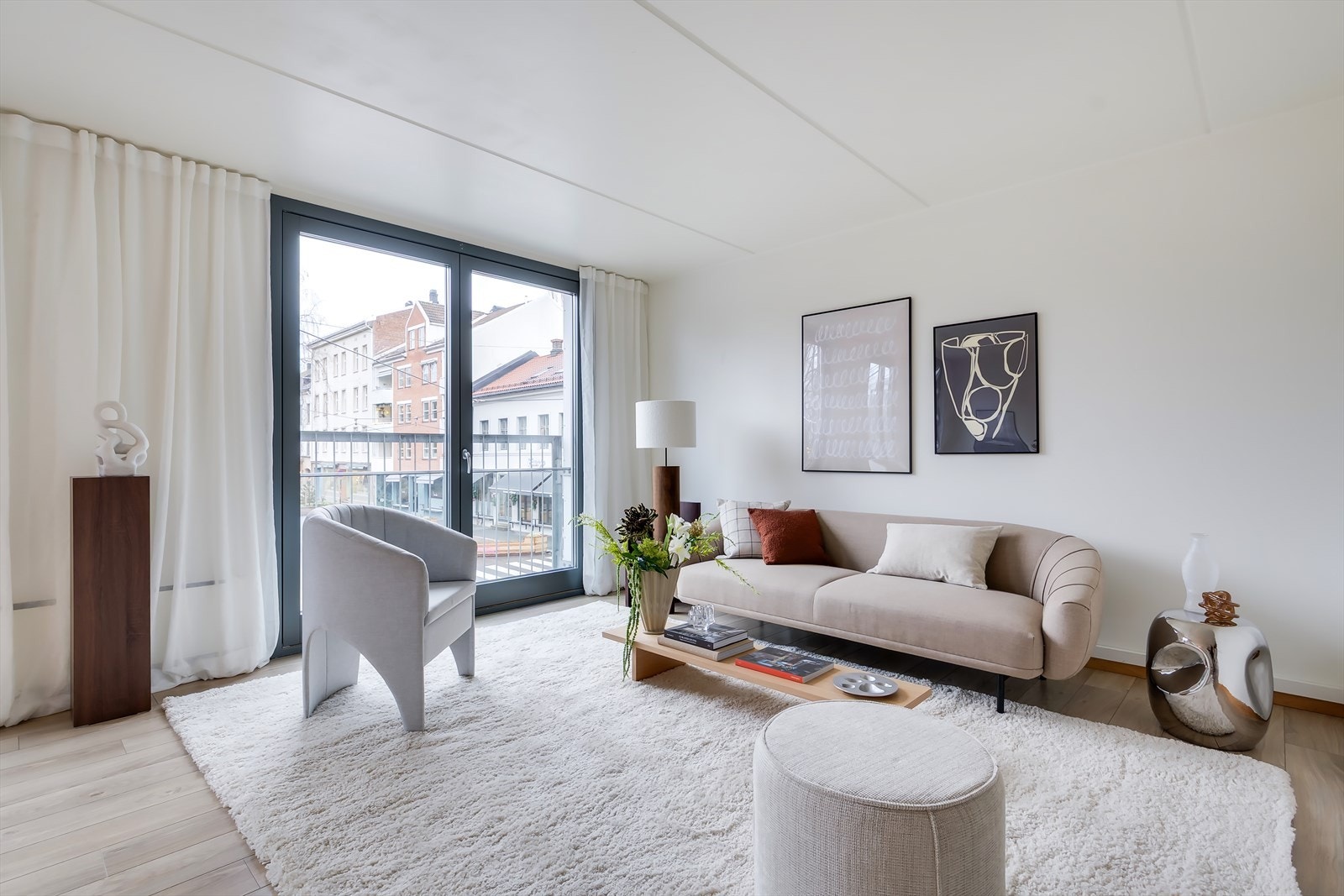 Lys og hyggelig stue med store vinduer og fransk balkong som slipper inn rikelig med naturlig dagslys og skaper en følelse av forlengelse av rommet. Galleribilde