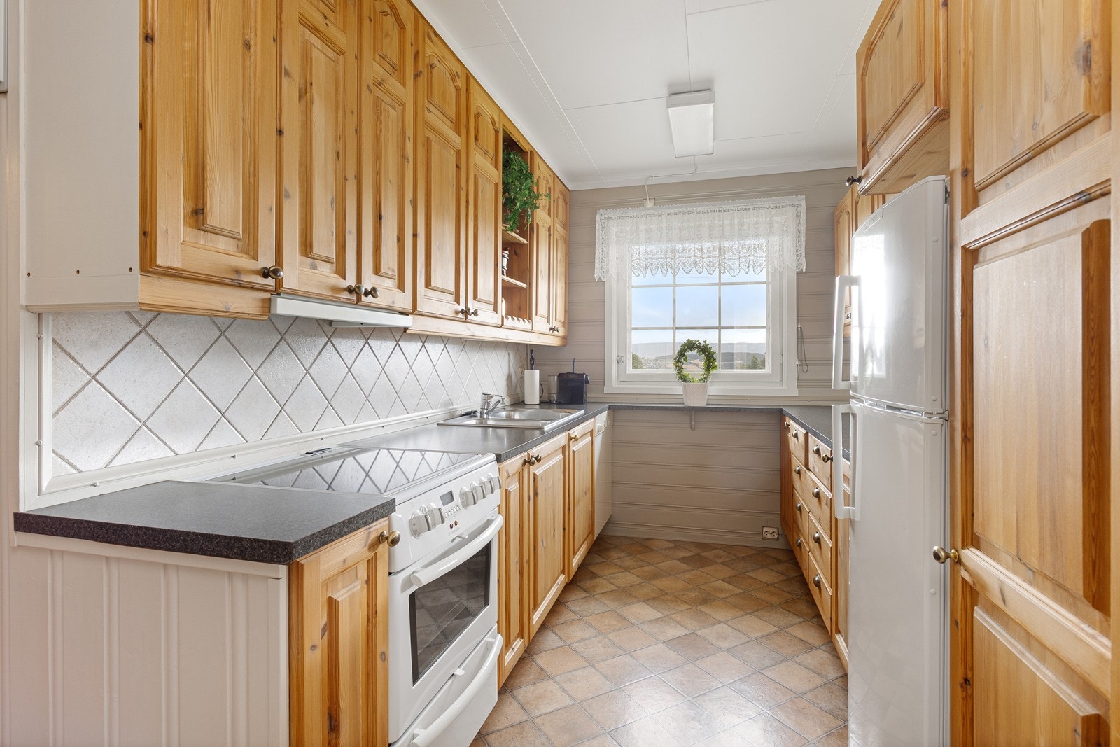 Kjøkkenet ligger i en delvis åpen løsning med tosidig innredning og plass til frittstående hvitevarer. Galleribilde