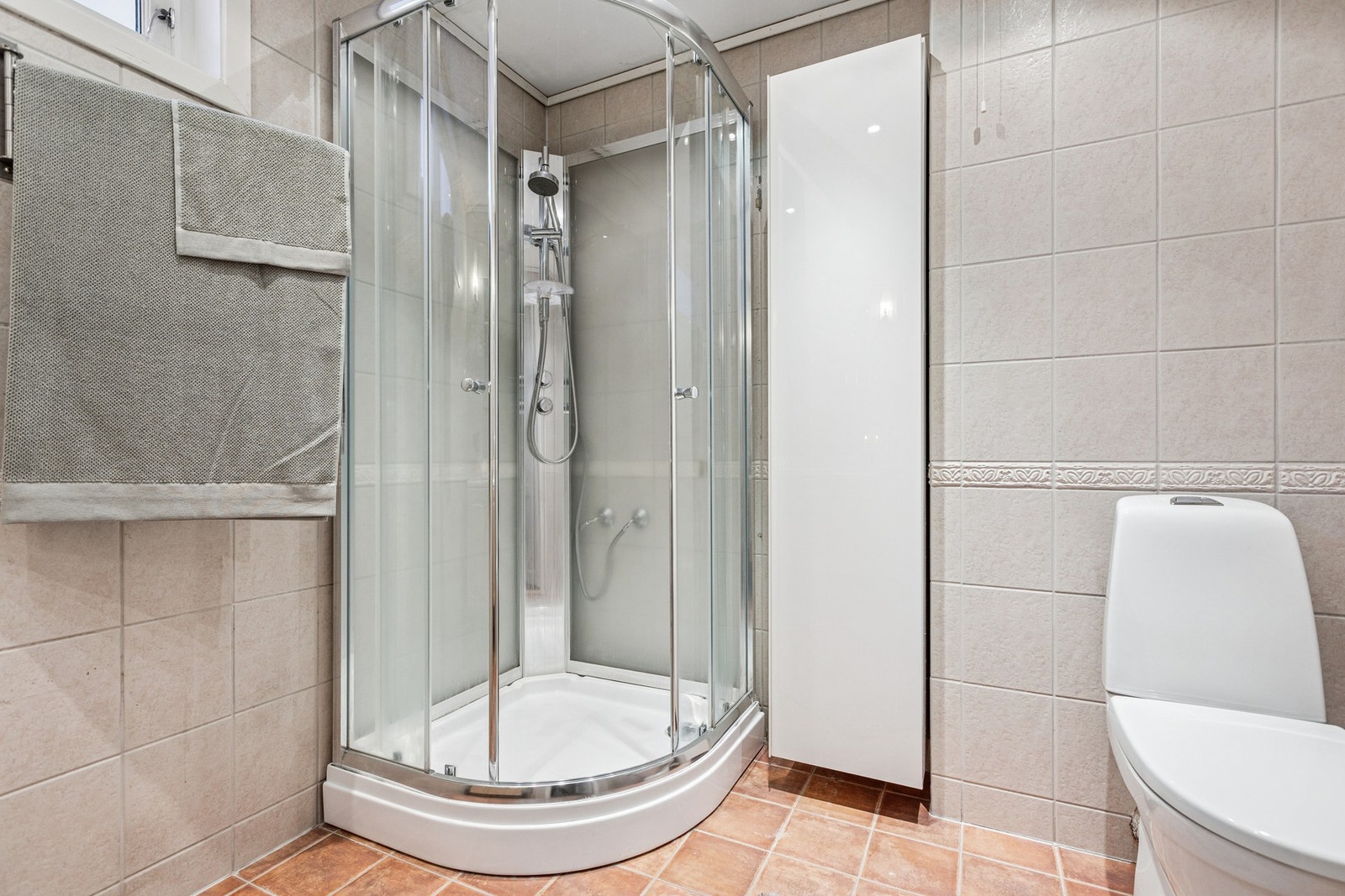 Badet er innredet med dusjkabinett, toalett, vegghengt høyskap og servantskap med speil. Galleribilde