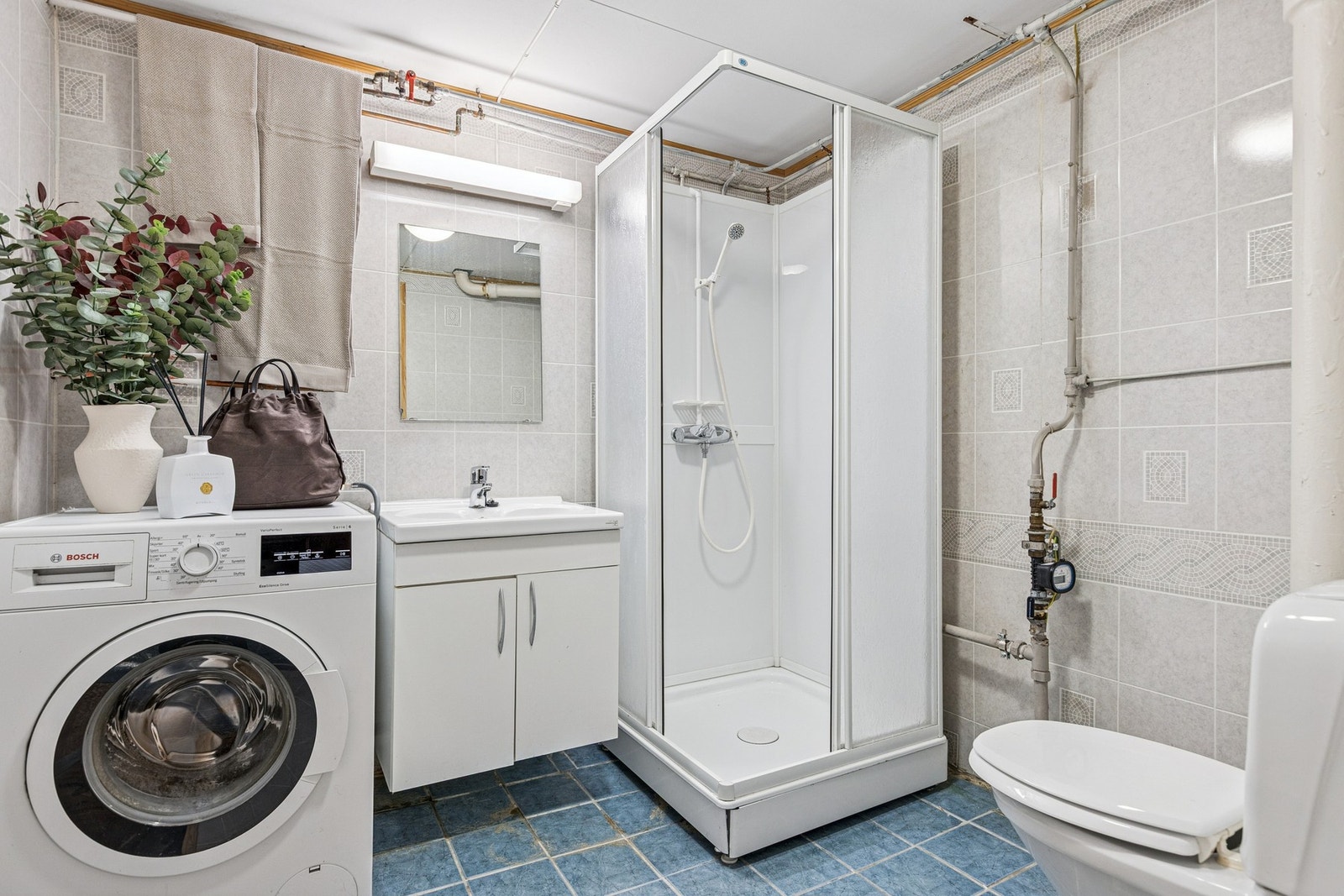 Badet er på 5 kvm og er innredet med dusjkabinett, toalett, vegghengt servantskap og vaskemaskin. Galleribilde