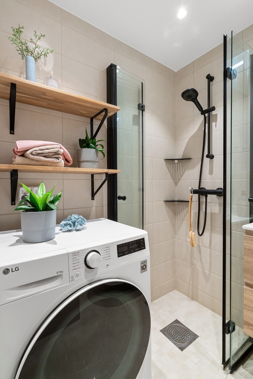 Badet har opplegg for vaskemaskinm hjørnedusj med glassdører, servant med skuffer, speilskap og toalett. Galleribilde