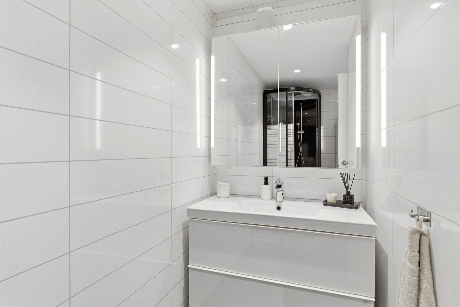 Bad med flis på gulv og plater på vegg. Moderne innredning og god belysning. Galleribilde