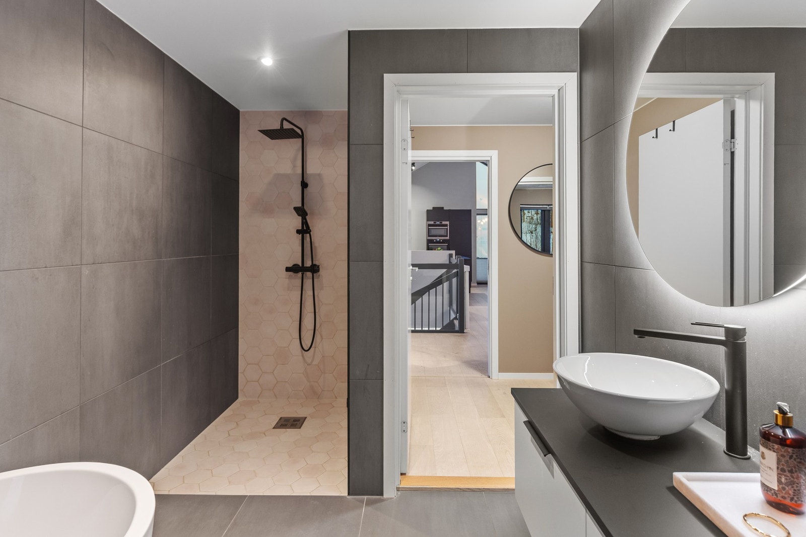 Badet er utstyrt med dusjnisje, frittstående badekar, veggmontert wc, mekanisk avtrekk og servantskap med servant. Galleribilde