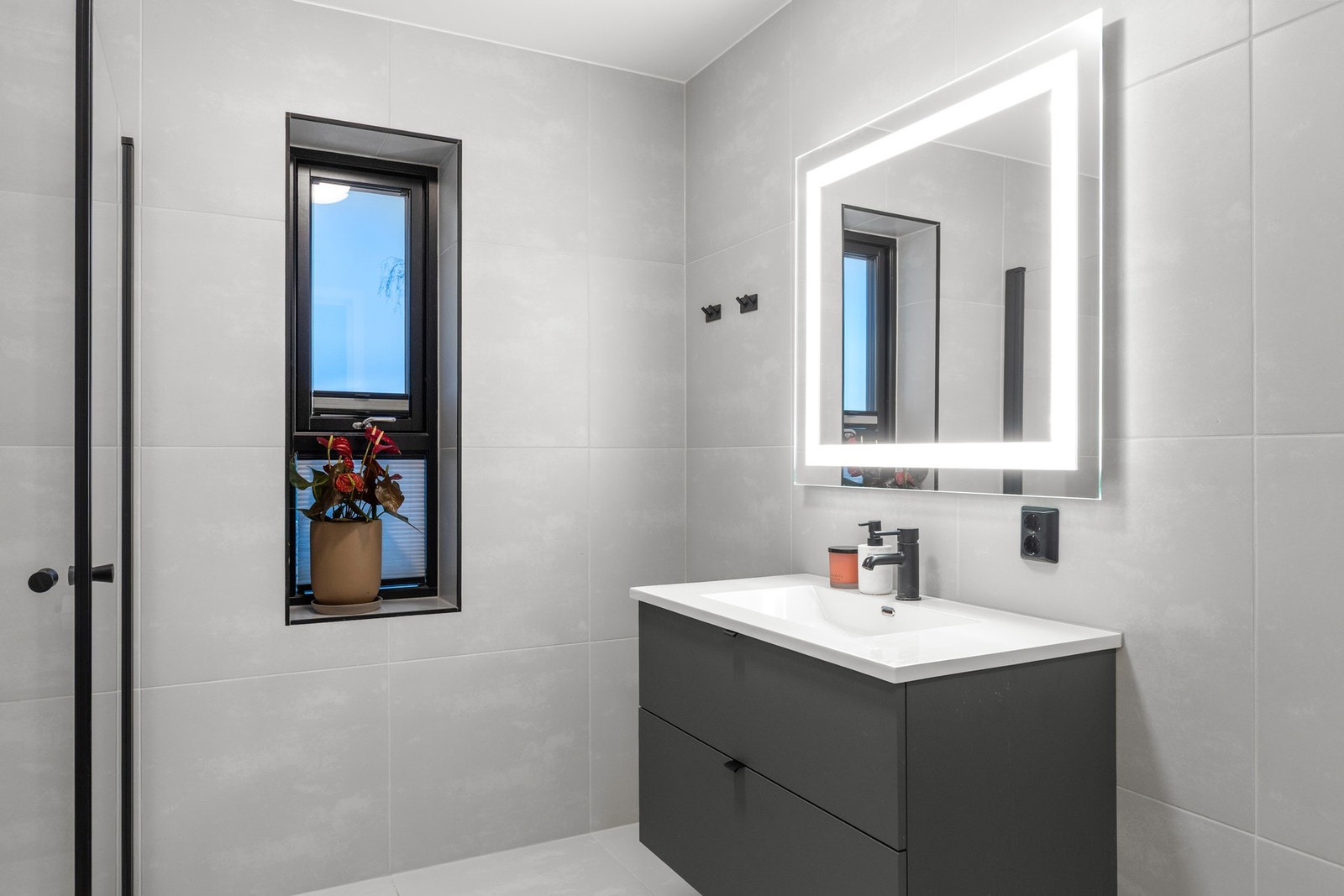 Badet er utstyrt med innfellbare dusjdører, mekanisk avtrekk, servantskap, servant og veggmontert wc. Galleribilde