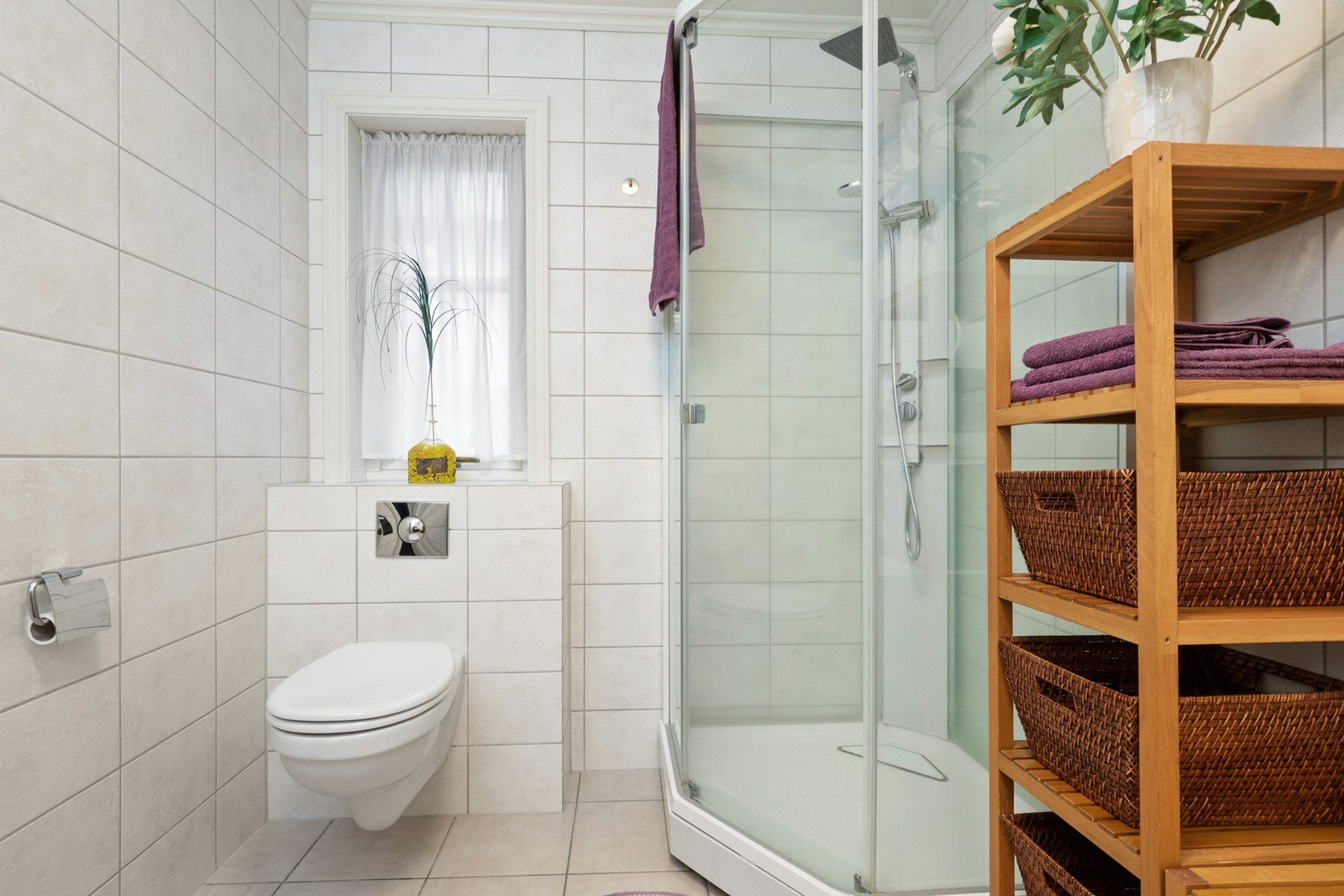 Badet har fine lyse fliser på vegger og gulv Galleribilde