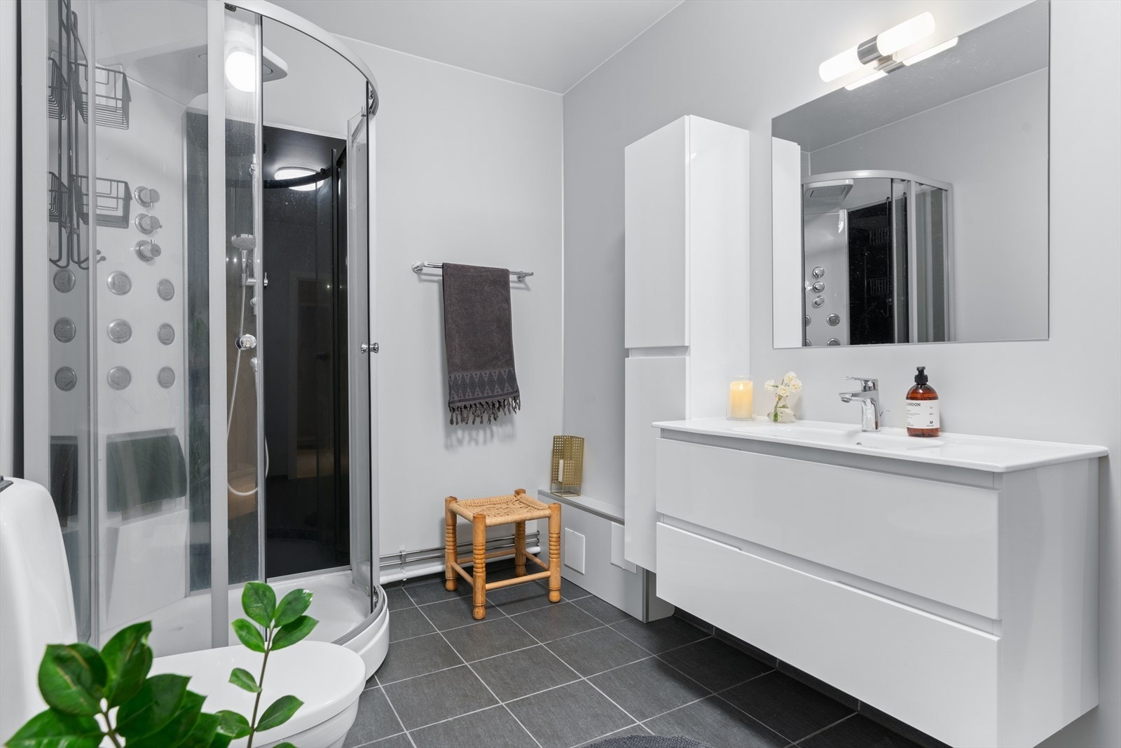 Flislagt bad med behagelig gulvvarme og godt med oppbevaring i innredning, samt opplegg for vaskemaskin. Nye overflater, innredning og dusj fra 2018. Galleribilde