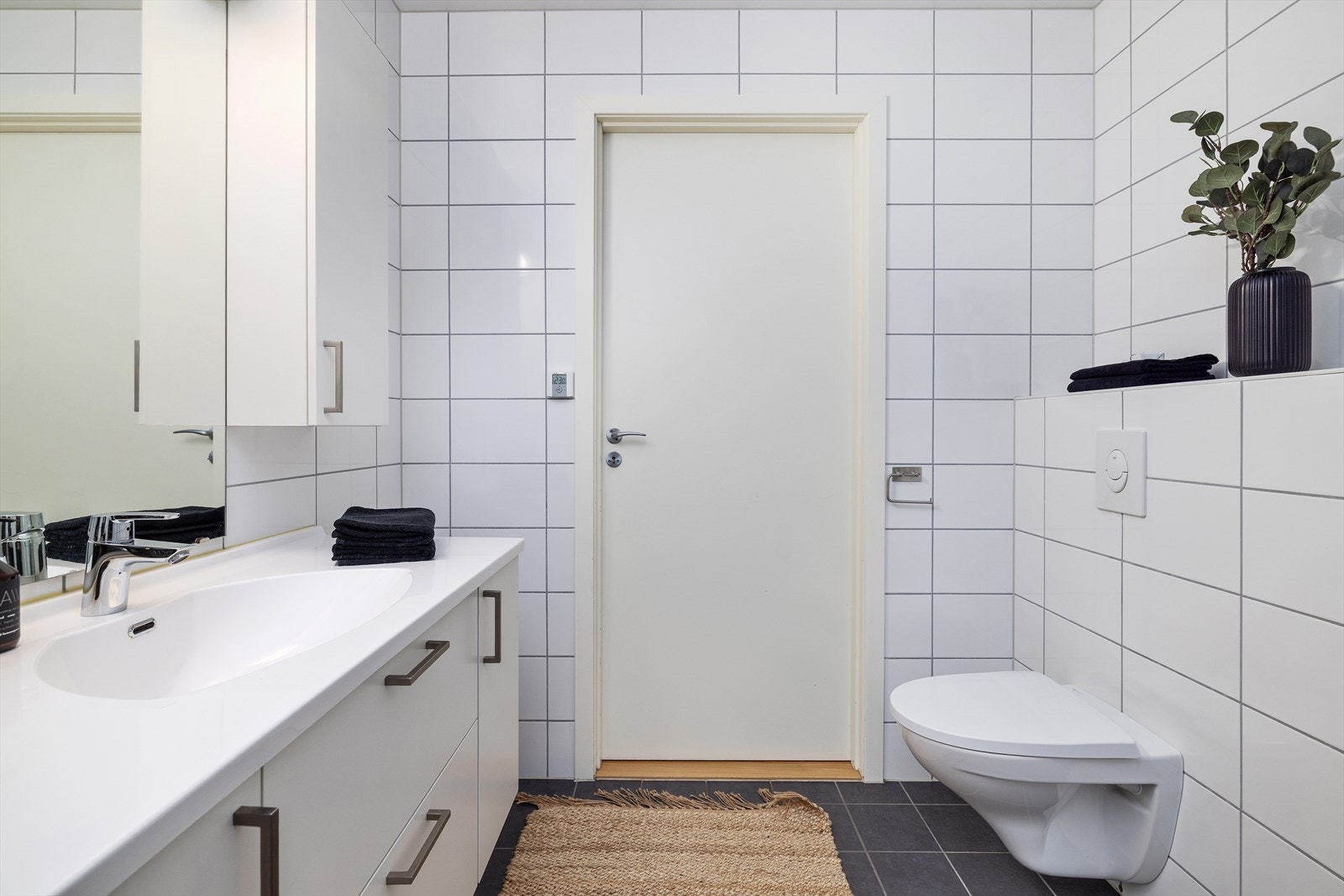 Lyst og delikat bad med vegghengt toalett og dusjnisje Galleribilde